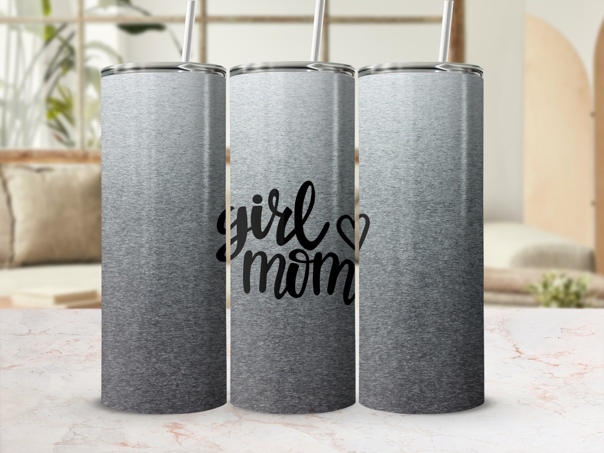 Silver ombre tumbler with "girl mom" text against a blurred background.