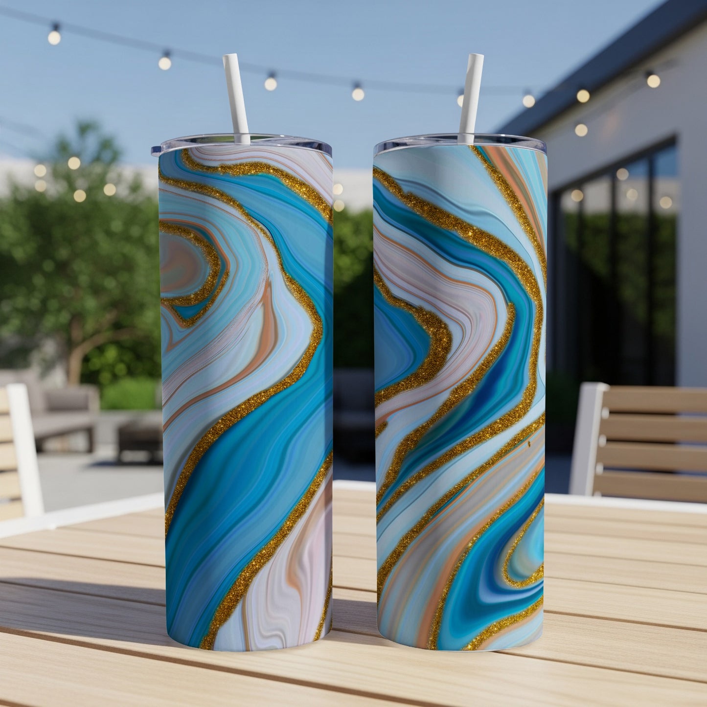 Two blue and gold marbled tumblers with straws on a table.