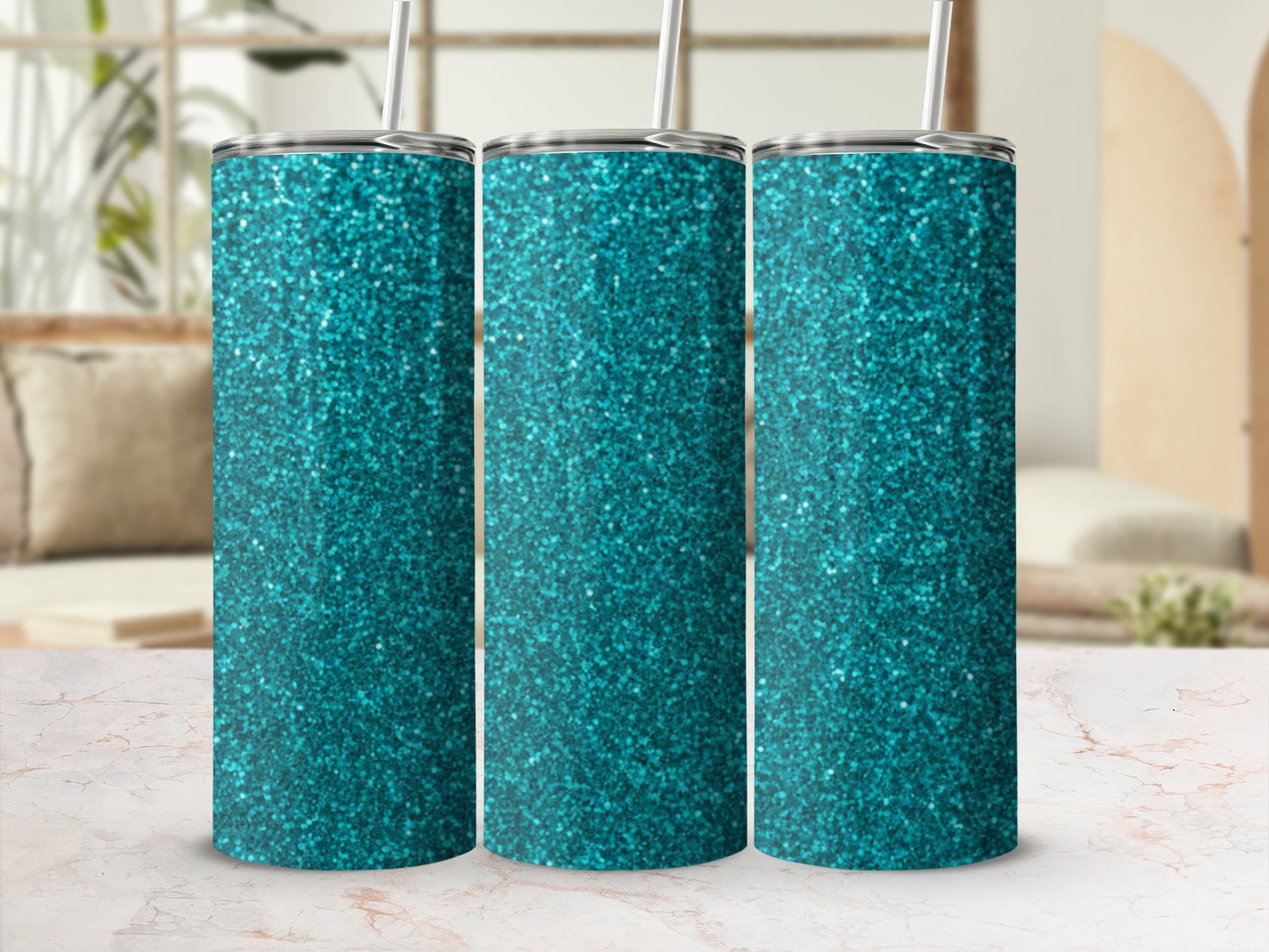 Three teal glitter tumblers with straws on a marble surface.