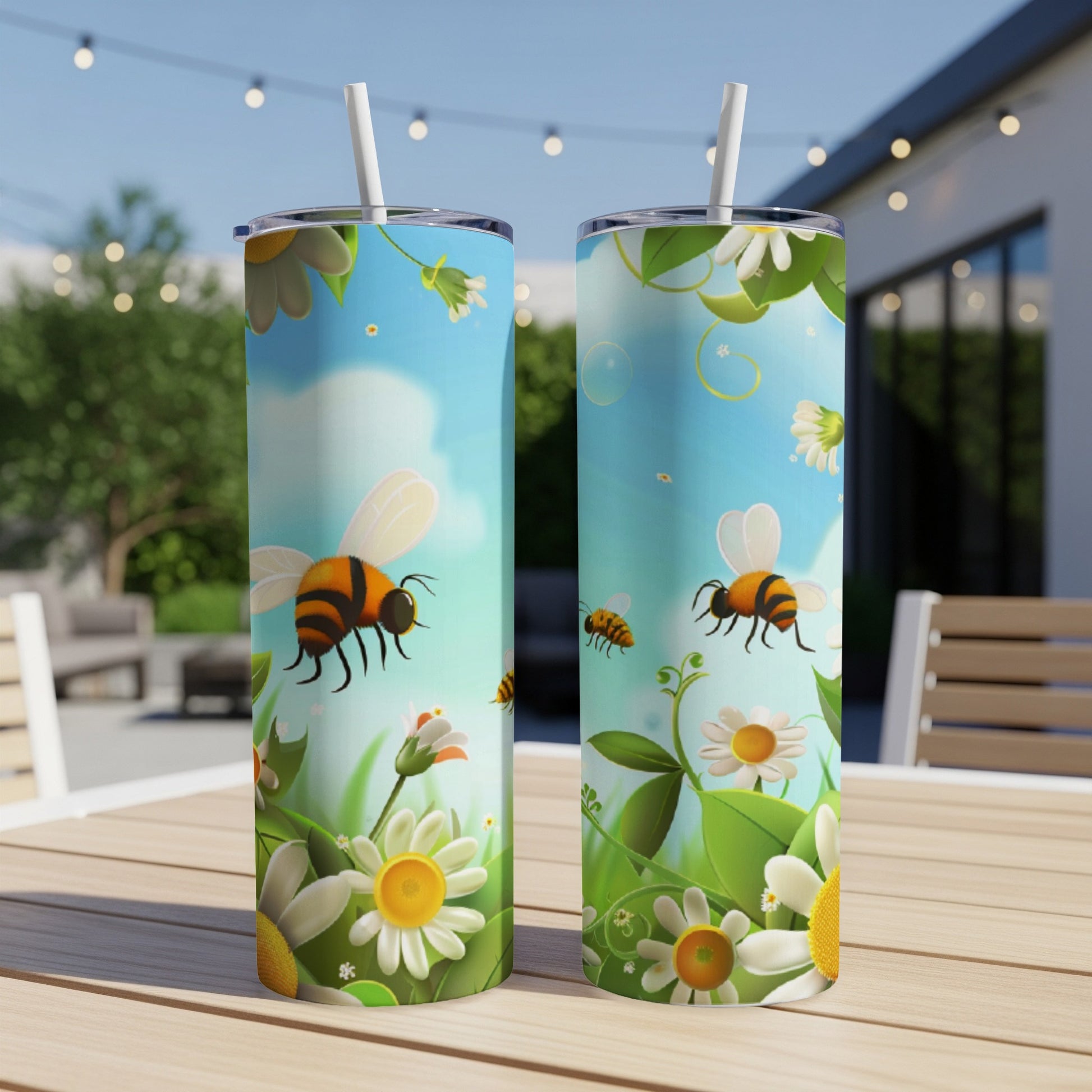 Two tumblers with bees and daisies on a table outdoors.