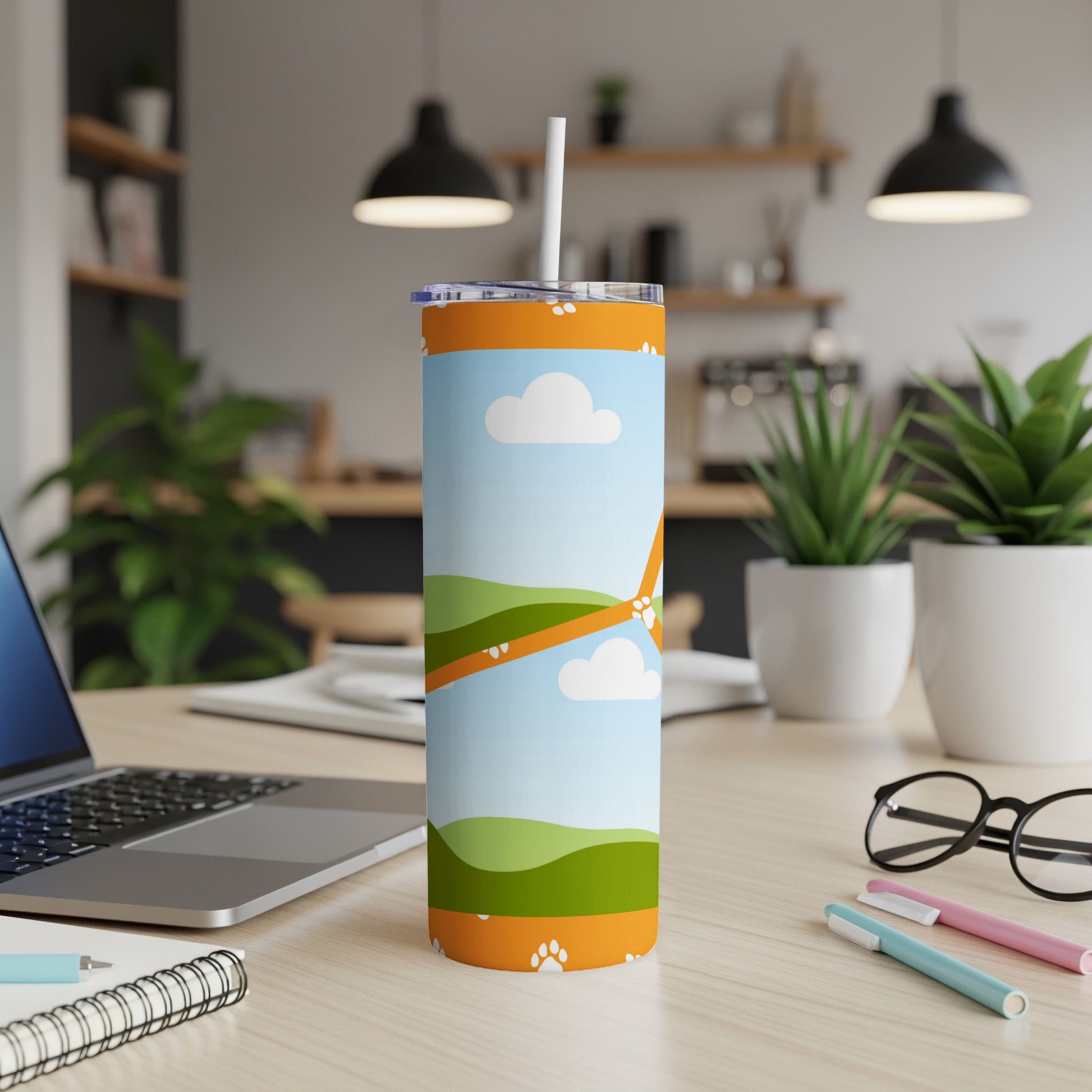 Tumbler with a whimsical landscape and paw print design, featuring a straw.
