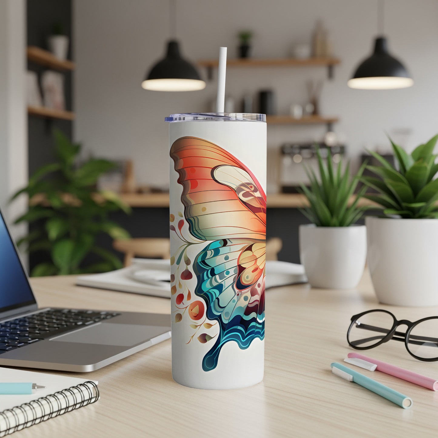 Butterfly patterned tumbler with straw on a desk.
