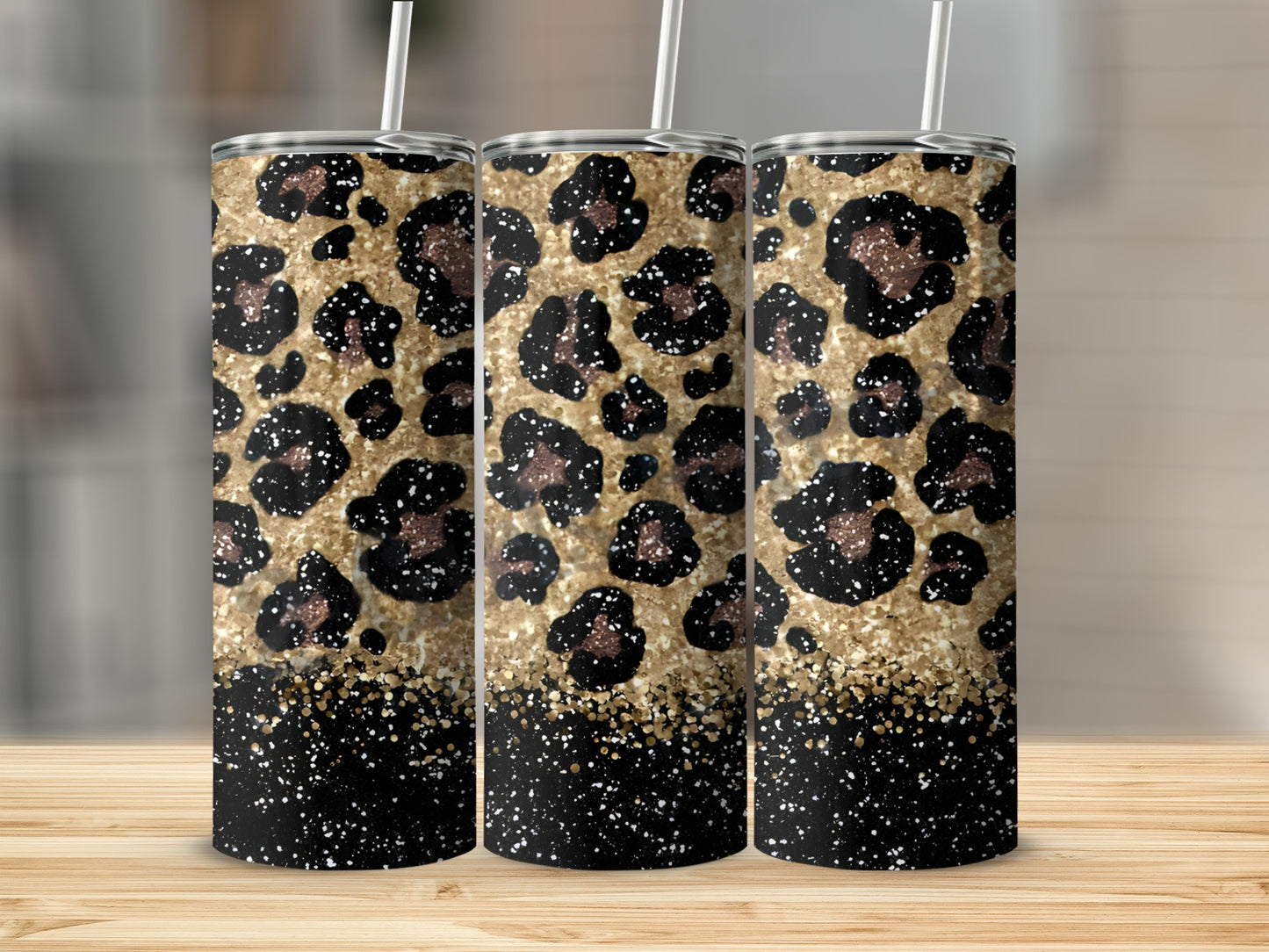 Three tumblers with leopard print and gold glitter design on a wooden surface.