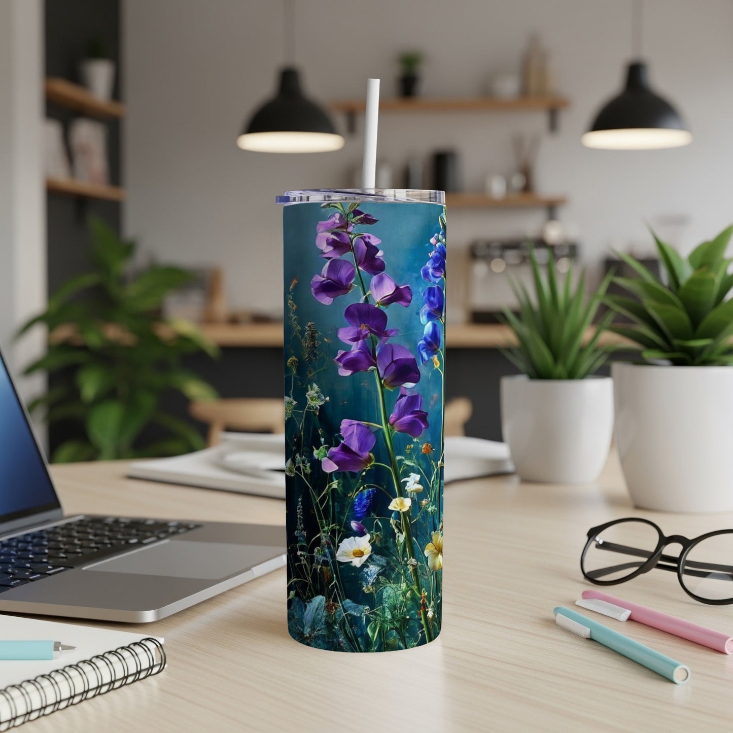 Tall tumbler with vibrant purple flowers and green leaves on a blue background.