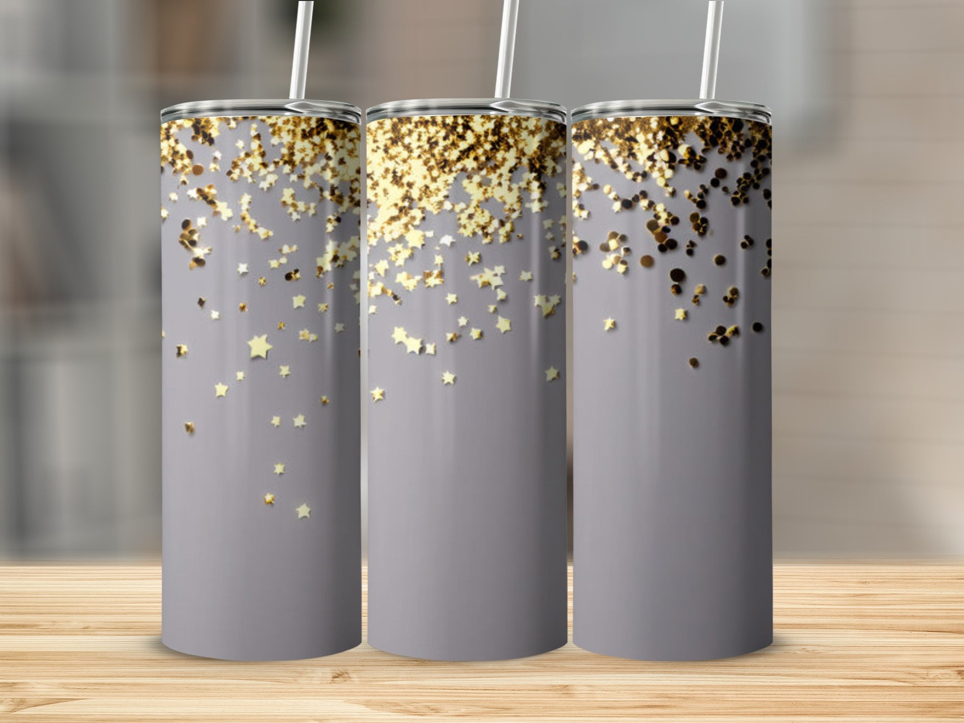 Three grey tumblers with a scattered gold glitter star pattern and white straws.