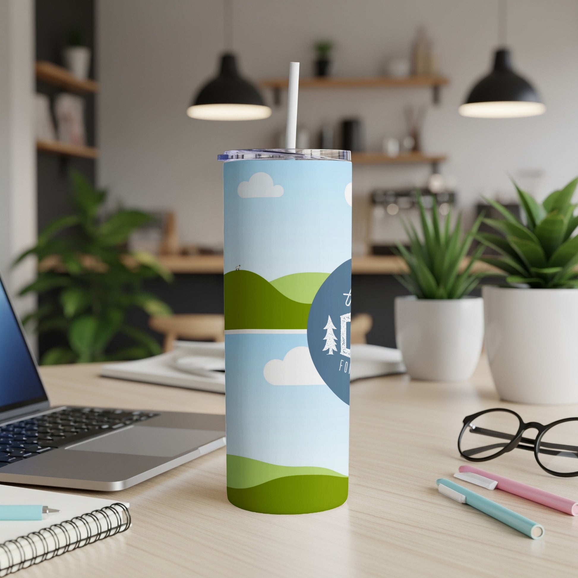 Tumbler with "THE ADVENTURE" text and landscape design on a desk.