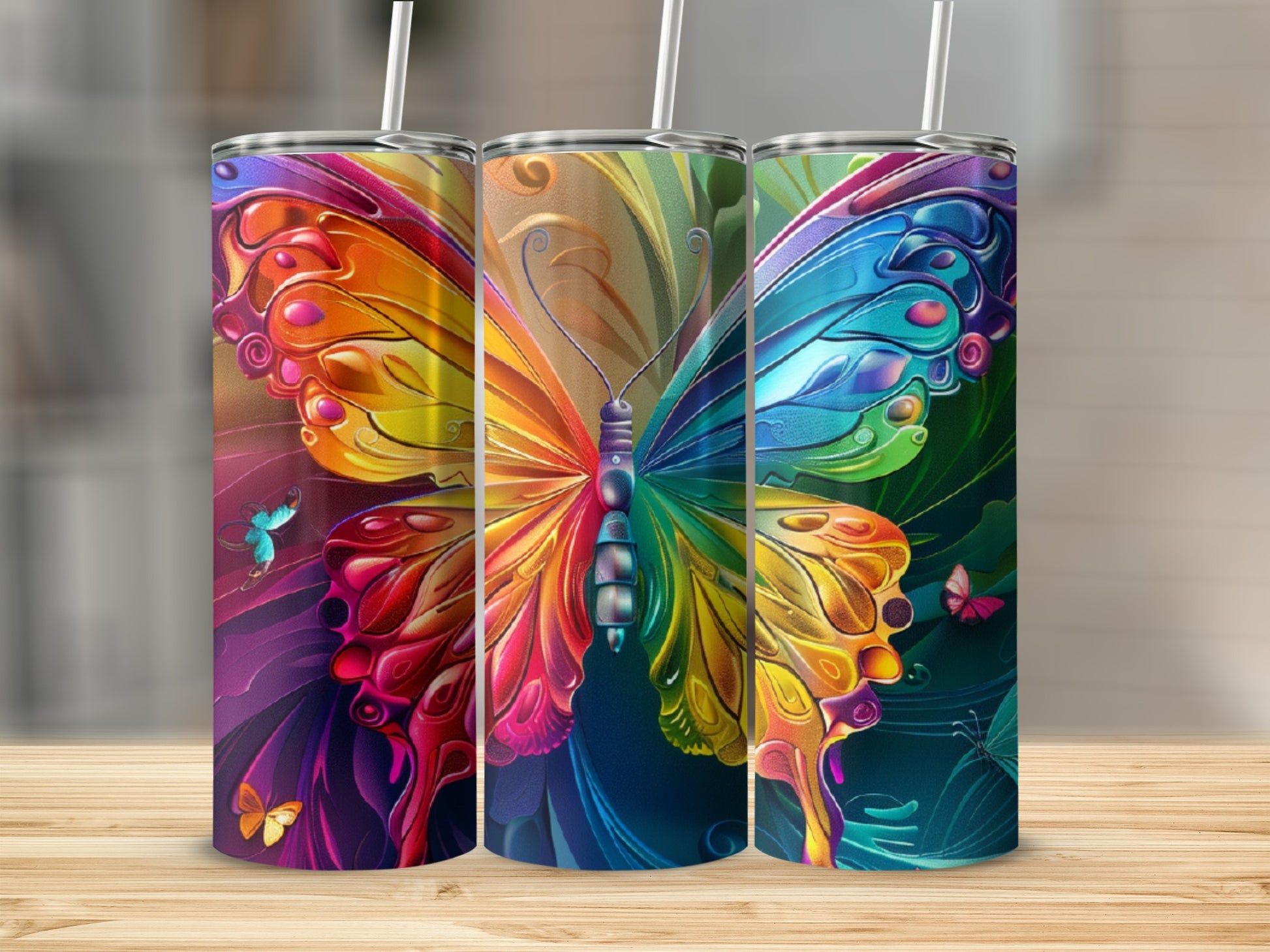 Three rainbow butterfly tumblers with straws displayed on a wooden surface.