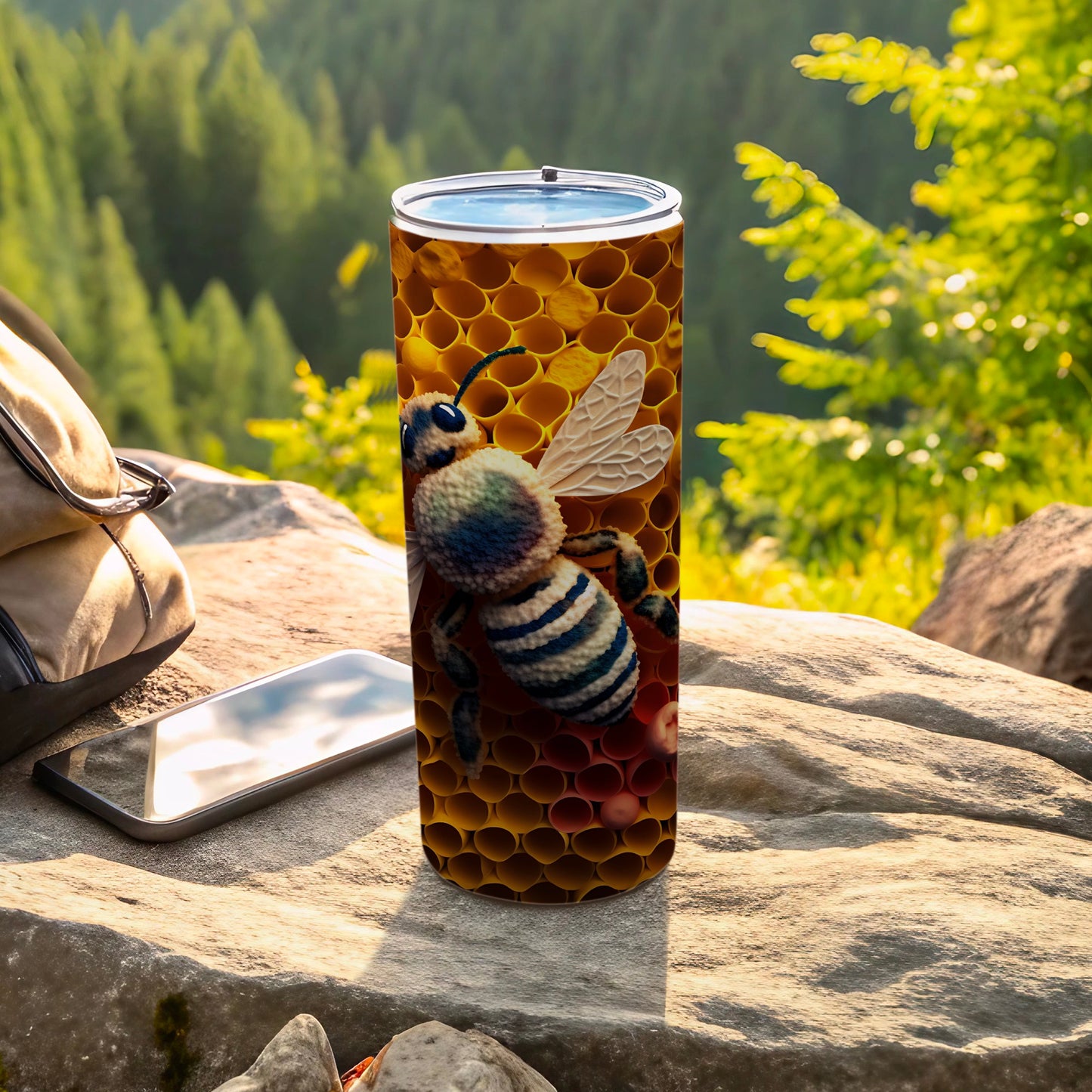Bee and honeycomb pattern on a stainless steel tumbler next to a phone and backpack.
