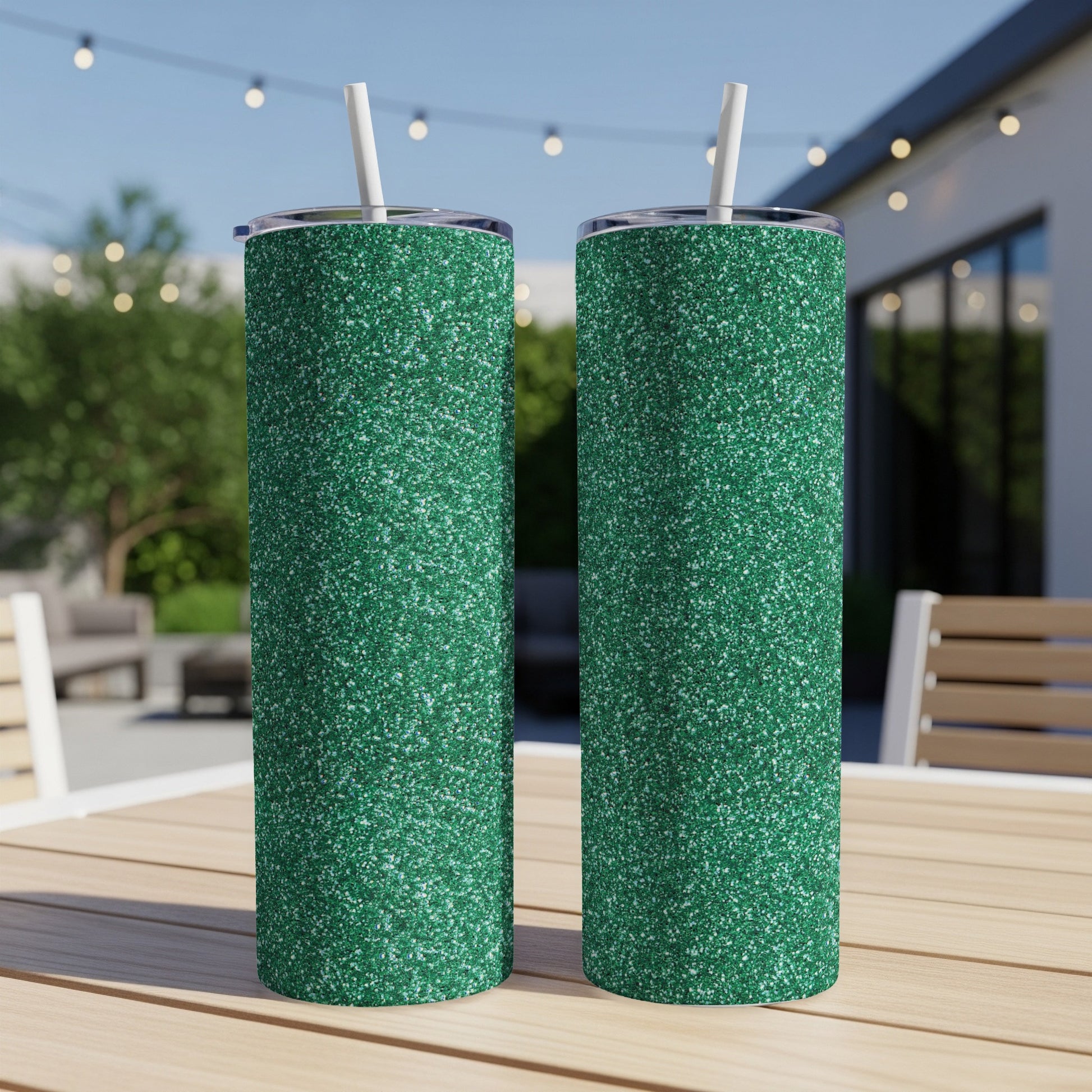 Two green glitter tumblers with white straws sit on a wooden table.