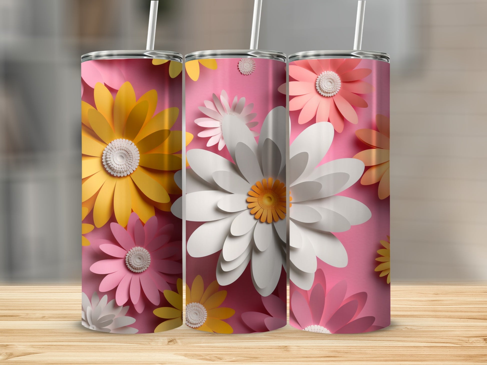 Three pink tumblers with colorful paper flower designs and straws.