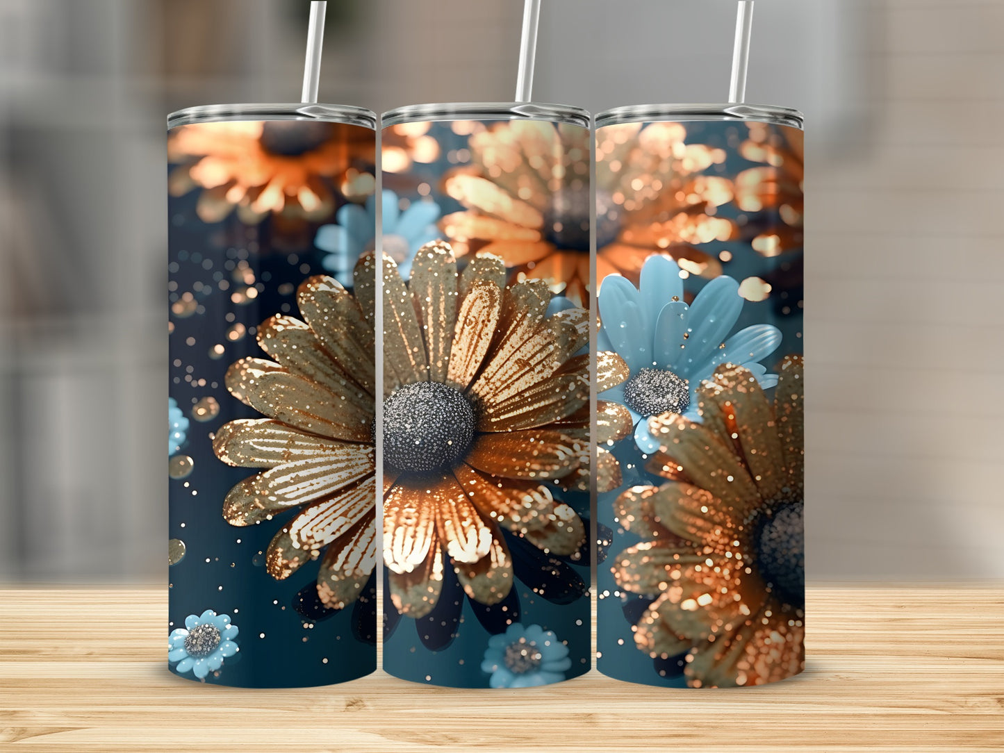 Three gold and blue glitter floral tumblers with straws on a wooden surface.