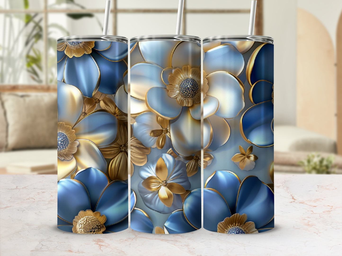 Three blue and gold floral tumblers with straws on a marble surface.