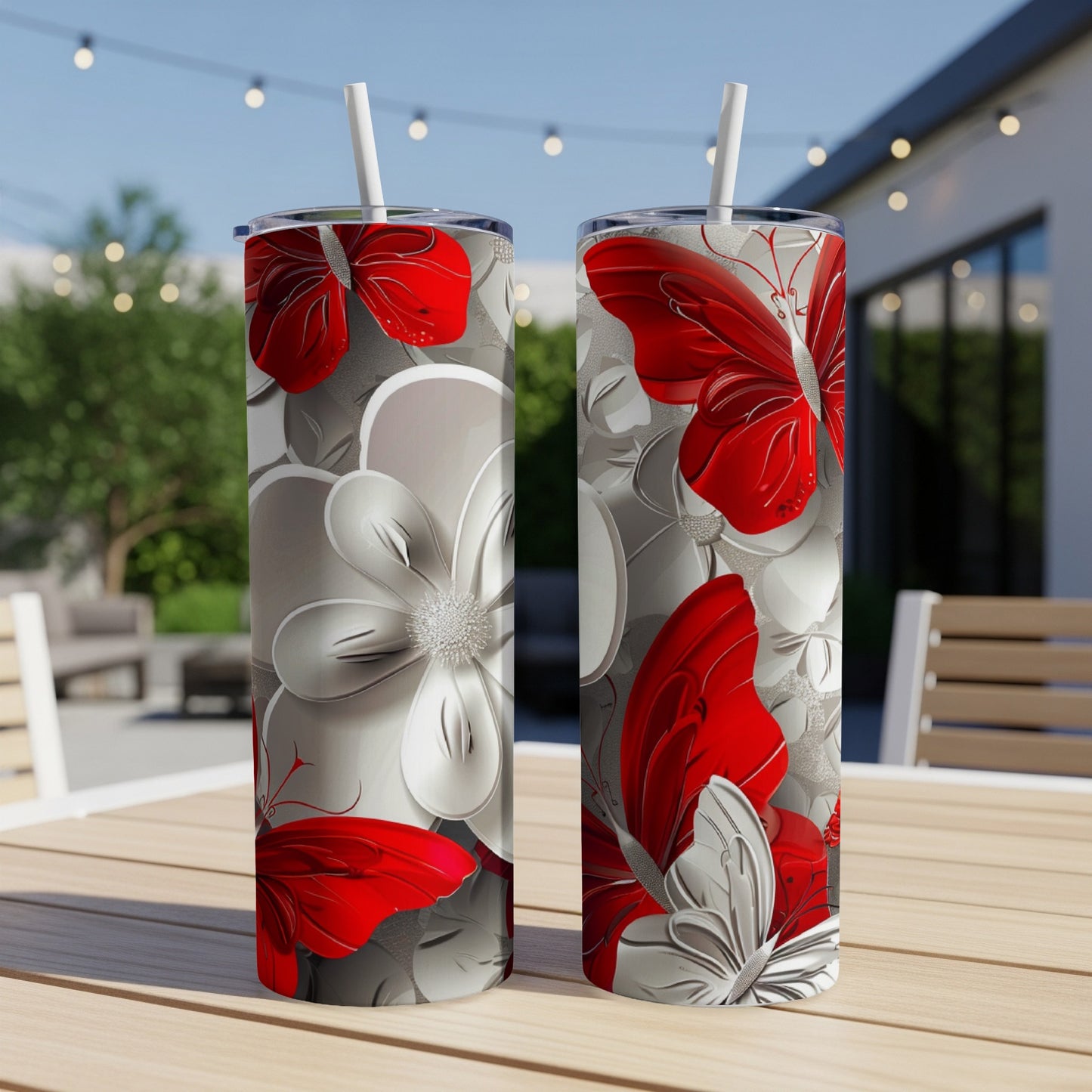 Two red and white floral patterned tumblers with butterfly accents on a table.