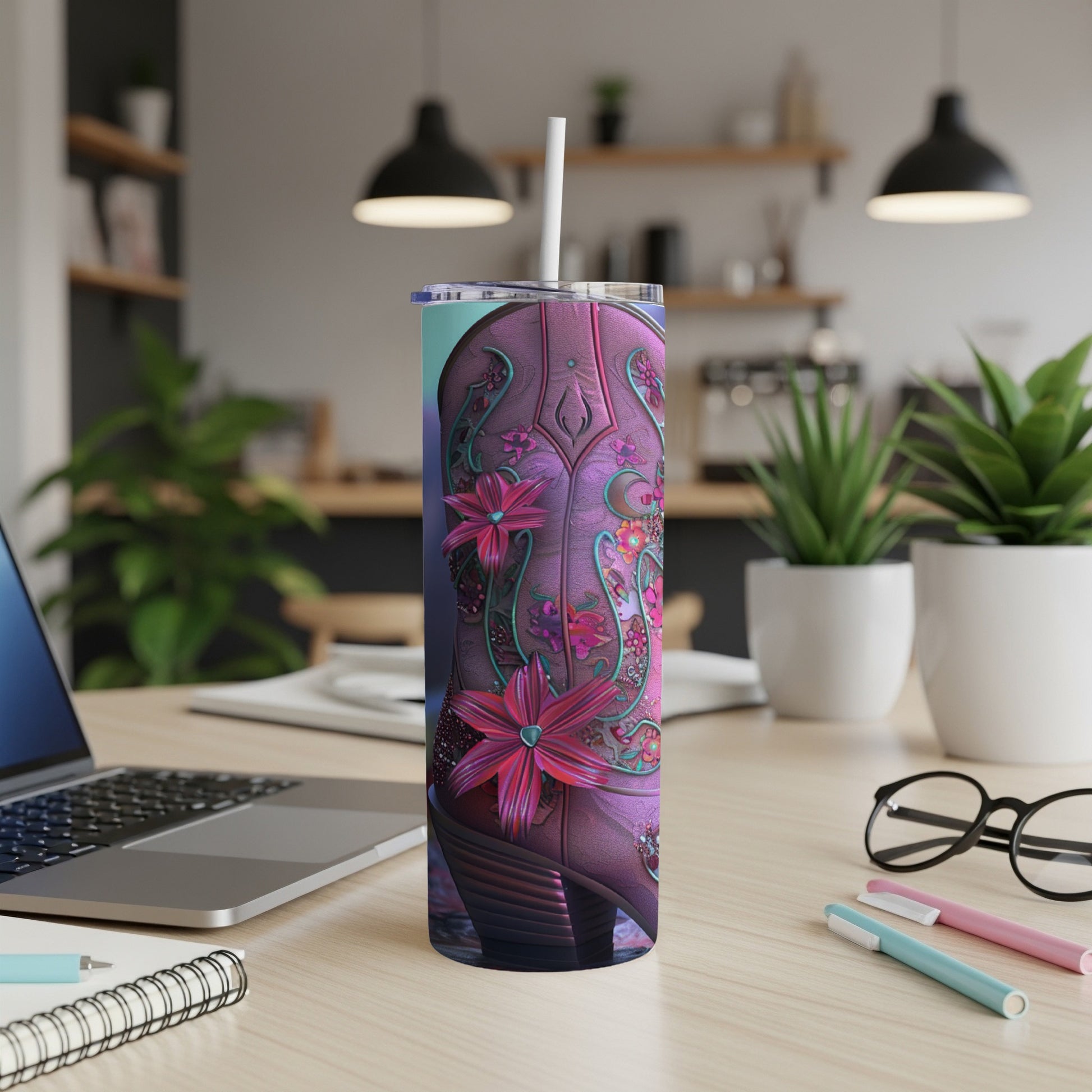 Pink floral cowboy boot tumbler with straw on a desk.
