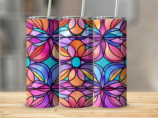 Three stained glass tumblers with vibrant floral patterns on a wooden surface.
