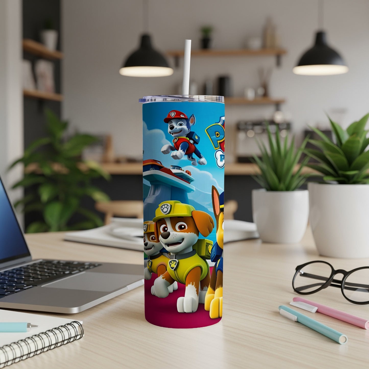 Paw Patrol characters on a pink tumbler with a laptop and art supplies.