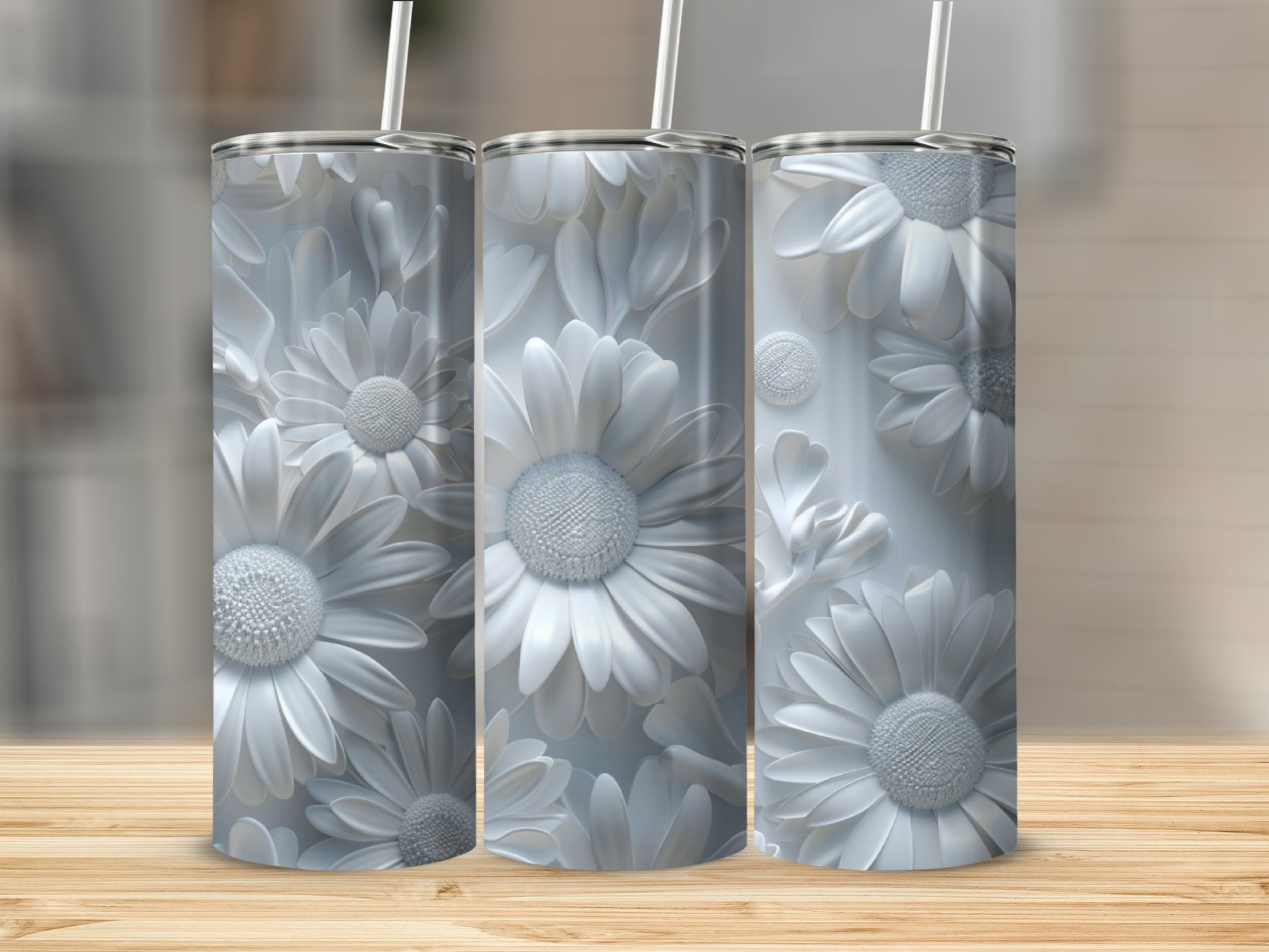 Three white floral pattern tumblers with straws on a wooden surface.