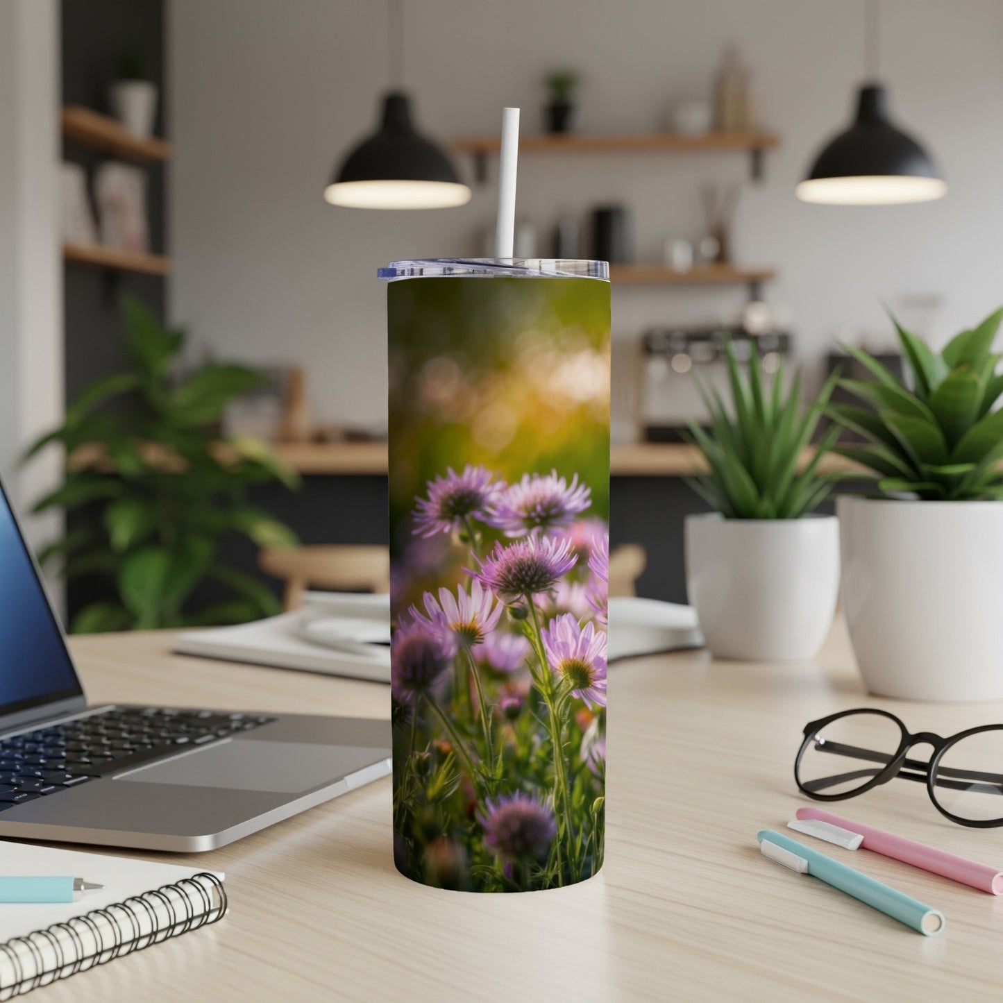 Purple aster flowers adorn a stainless steel tumbler on a desk.