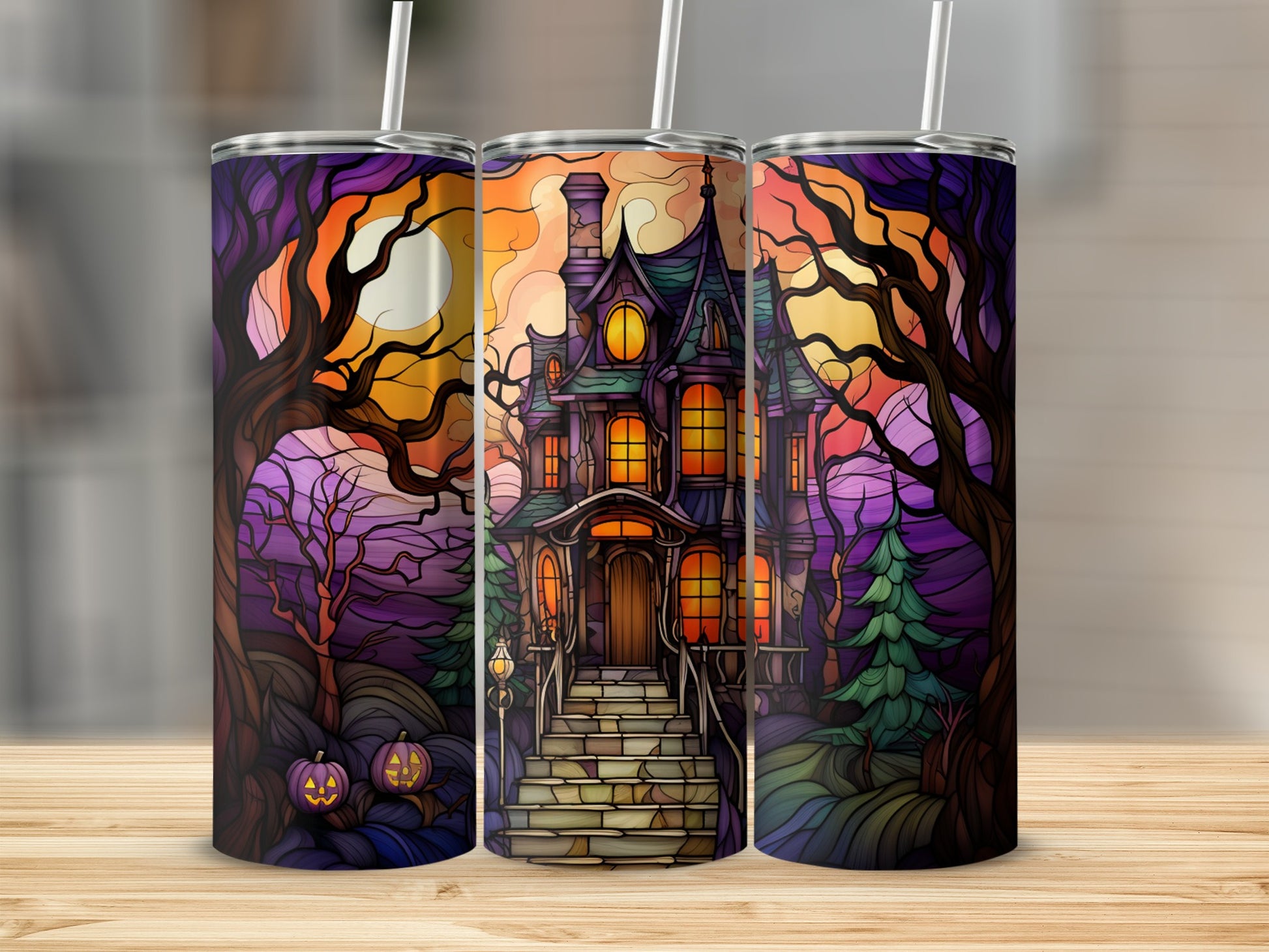 Three Halloween tumblers with a haunted house design, pumpkins, and trees.