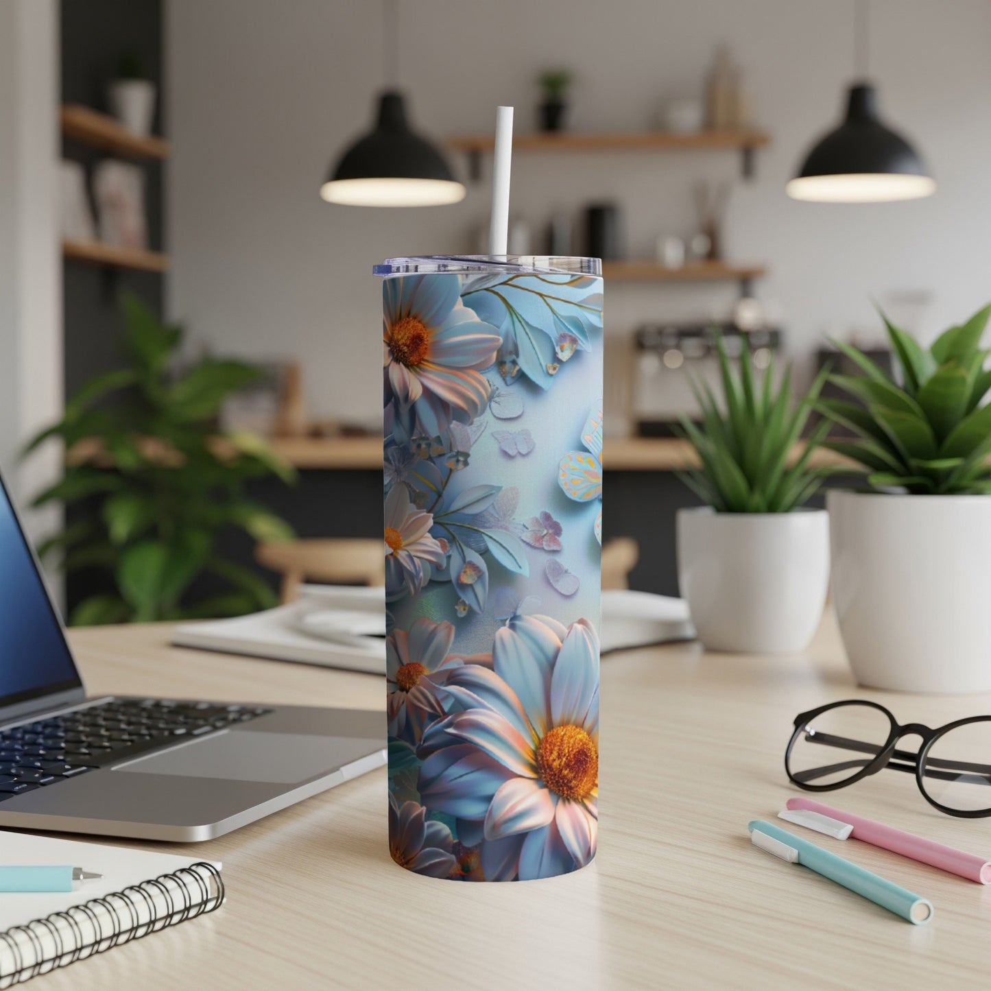 Tall tumbler with blue and pink floral pattern and straw on a desk.
