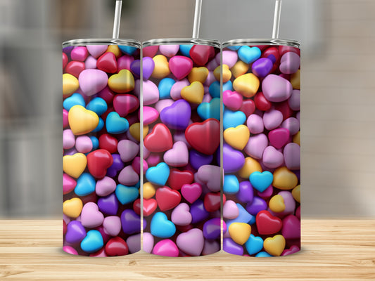 Multi-colored heart pattern on three tumblers with straws.