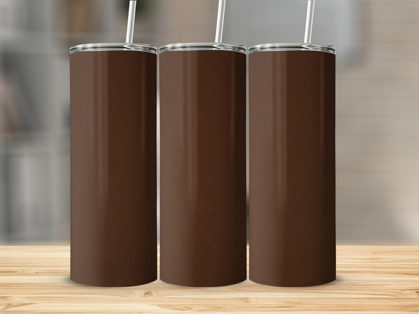 Three plain brown tumblers with straws on a wooden surface.