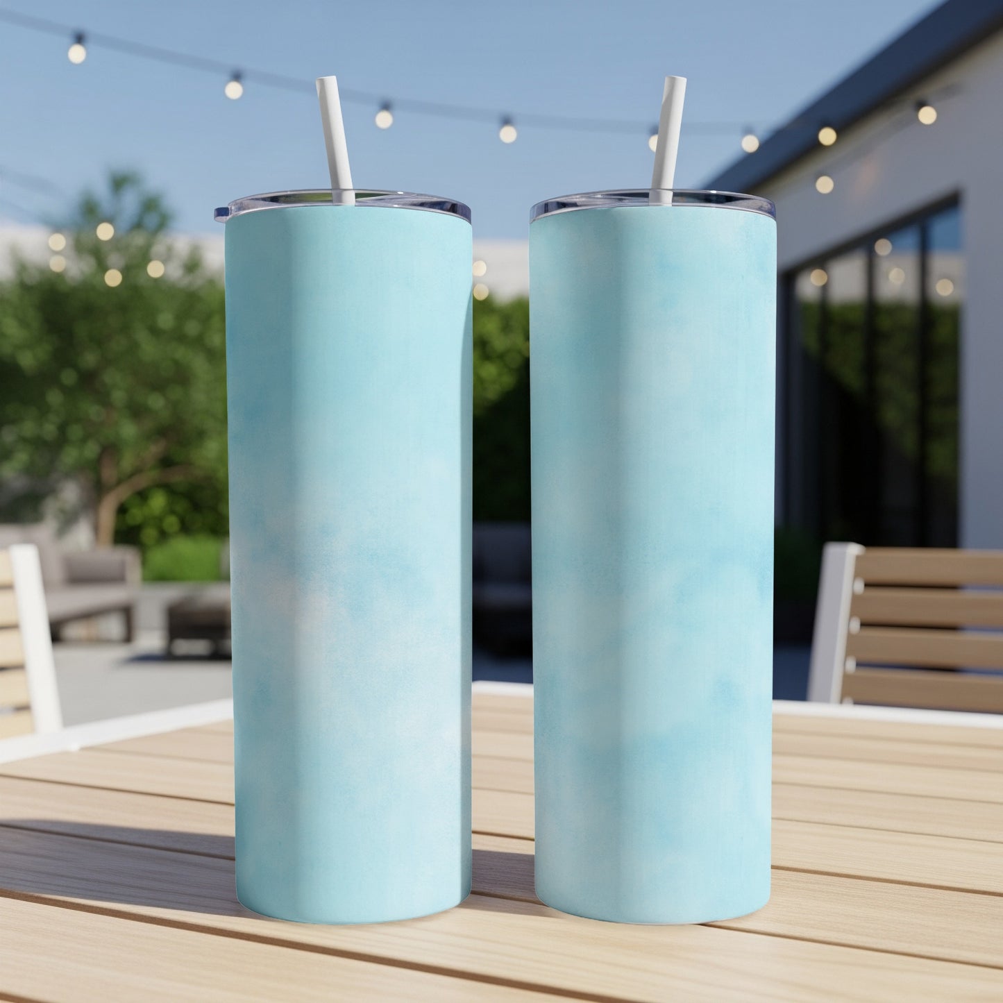 Two tall, light blue marbled tumblers with straws on a wooden table.