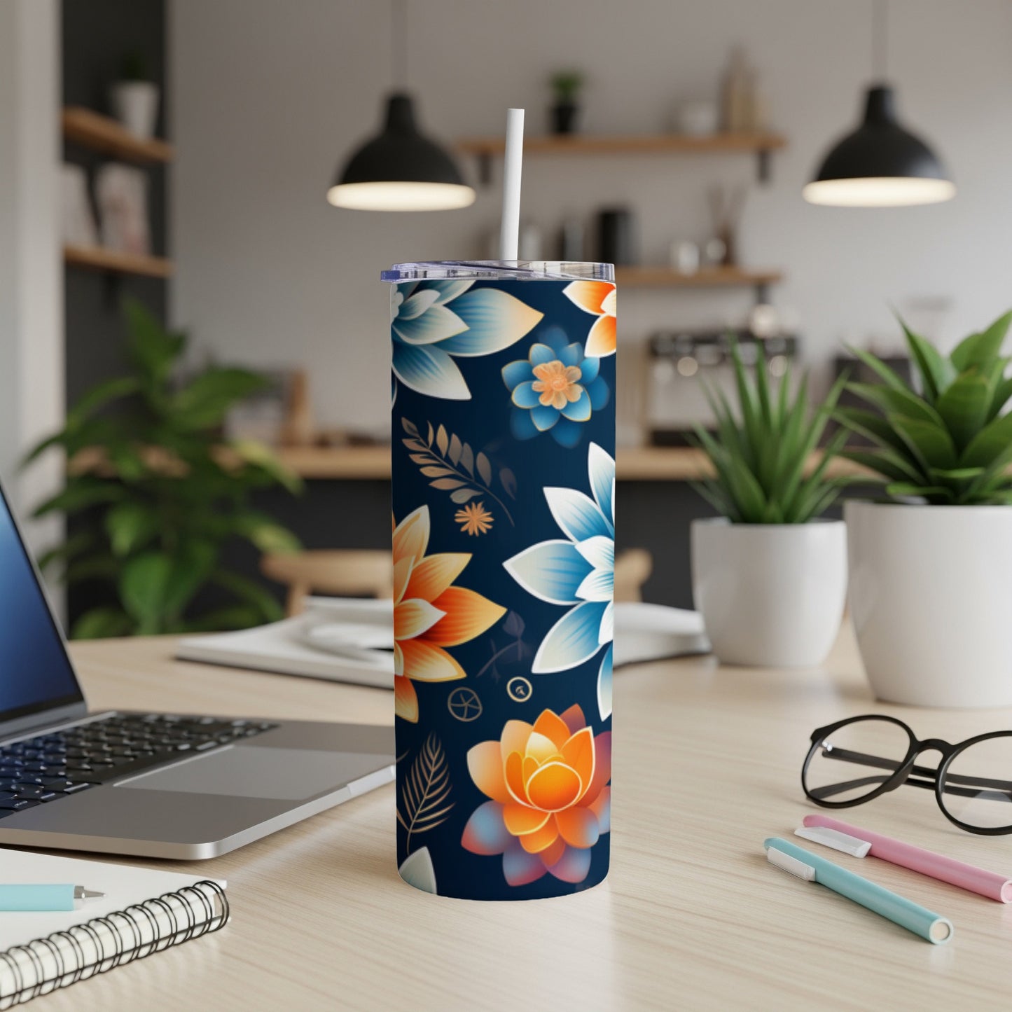 Dark navy tumbler with colorful floral pattern and white straw on a desk.