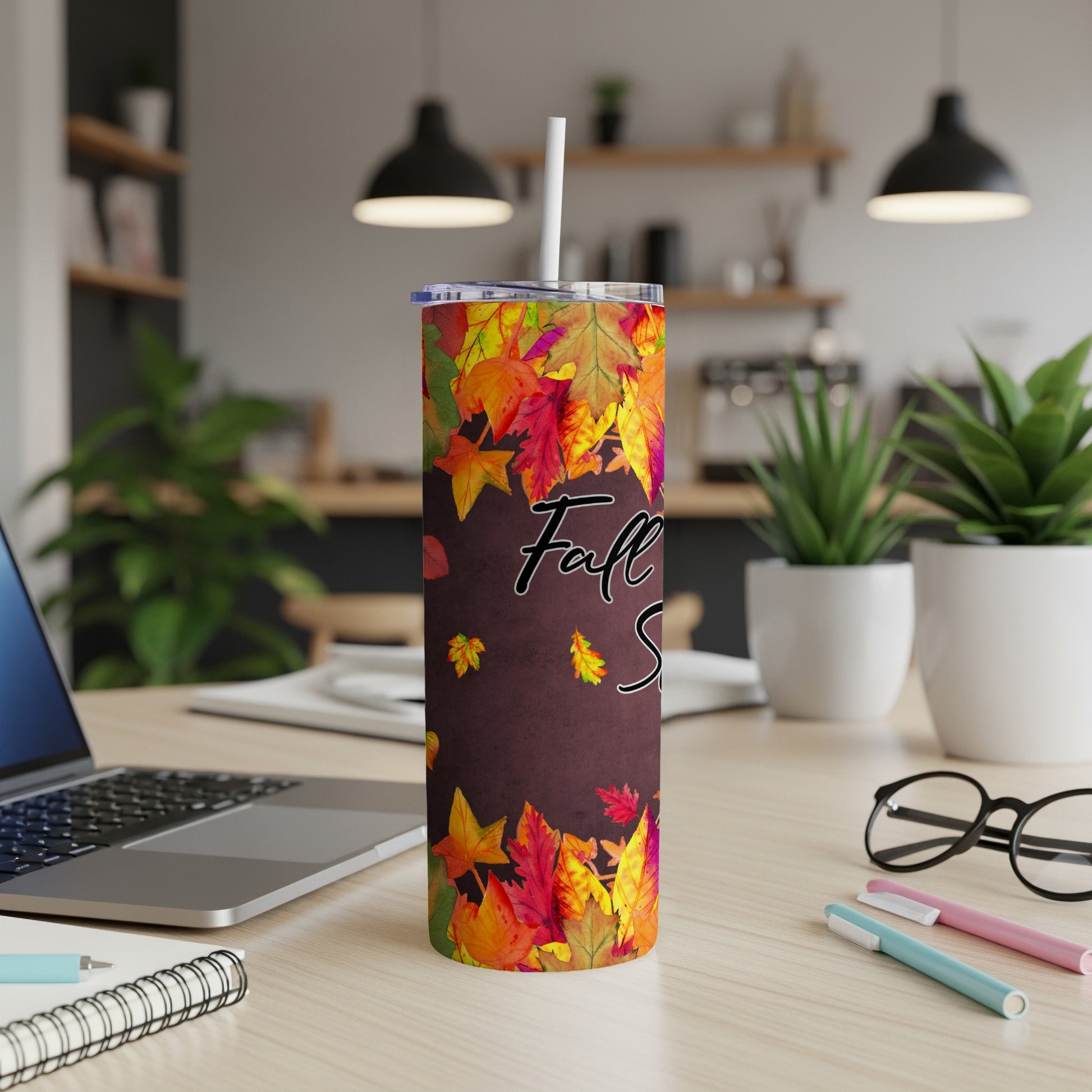 Tumbler with colorful fall leaves and text "Fall Vibes" on a desk.