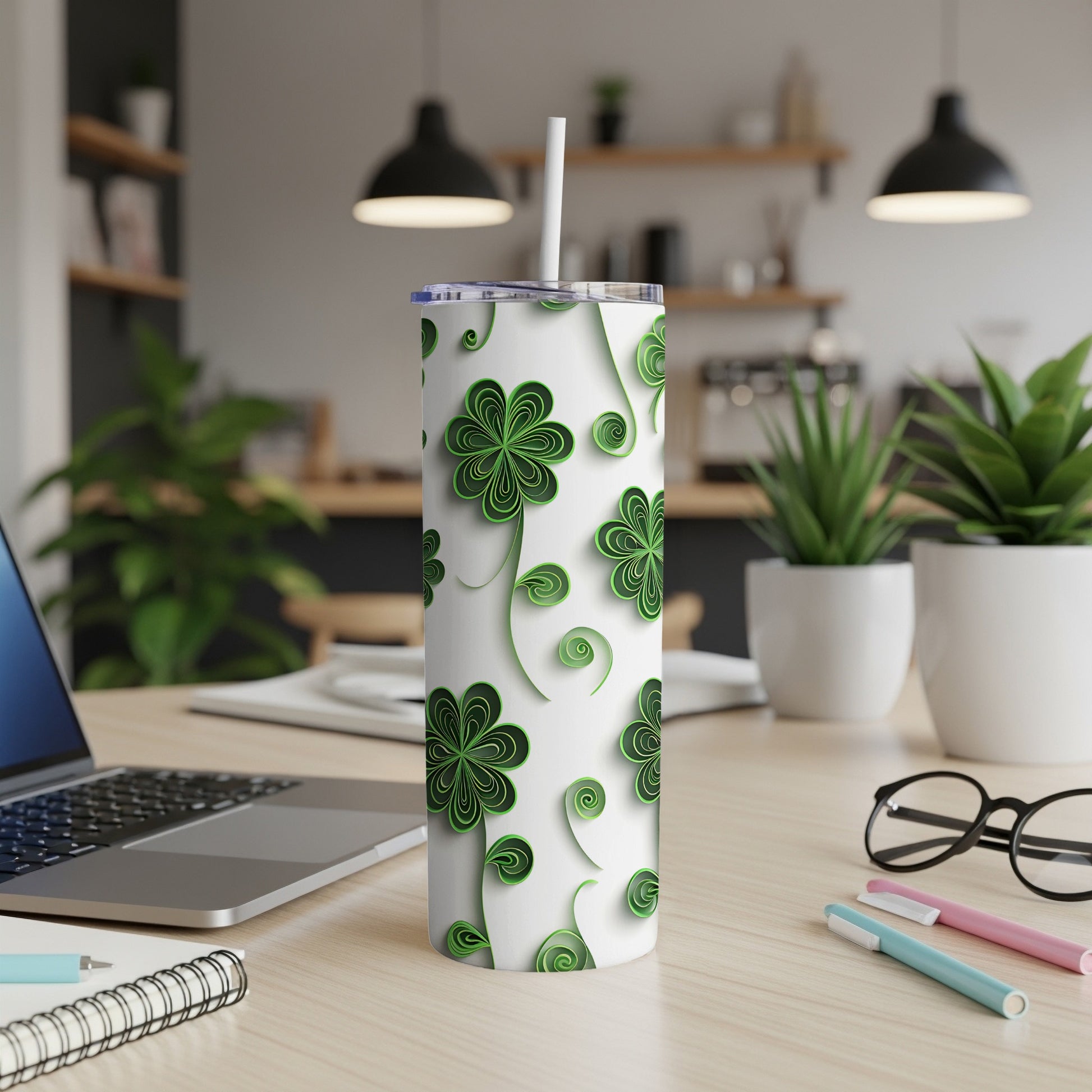 White tumbler with green clover pattern, straw, and office desk background.