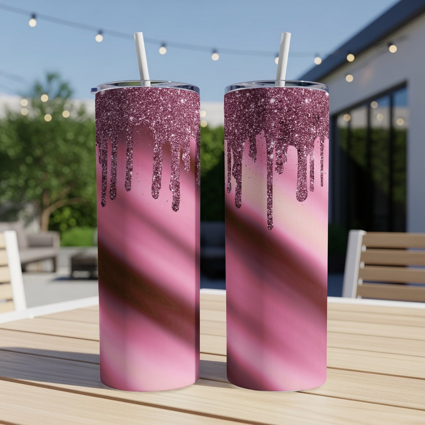 Two pink glitter drip tumblers with white straws on a wooden table.
