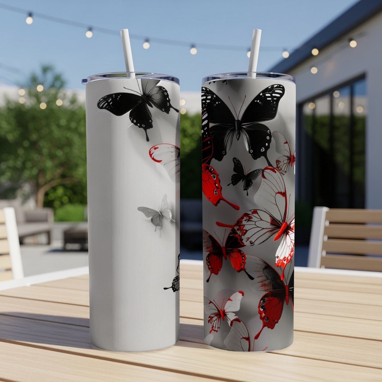 Two tumblers with grayscale and red butterflies on a table.