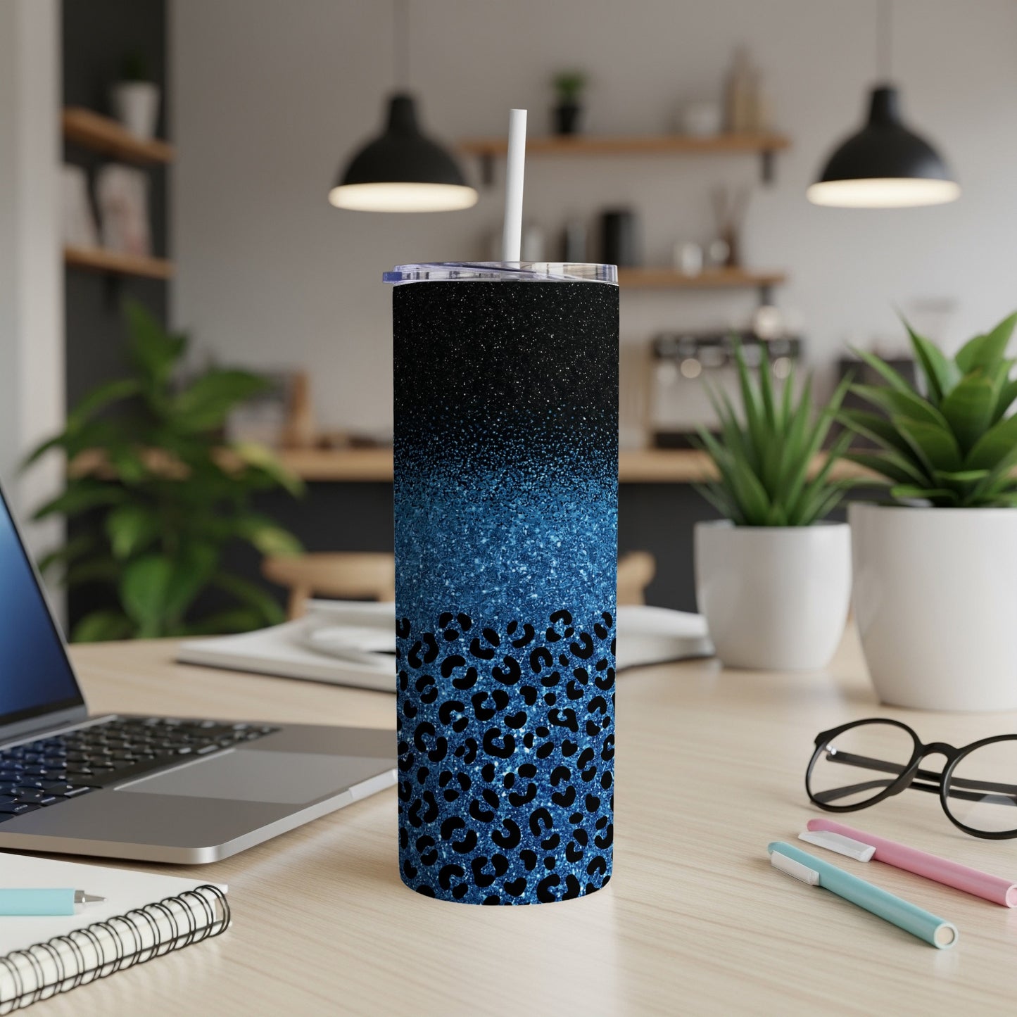 Glittering blue leopard print tumbler with straw on a desk.