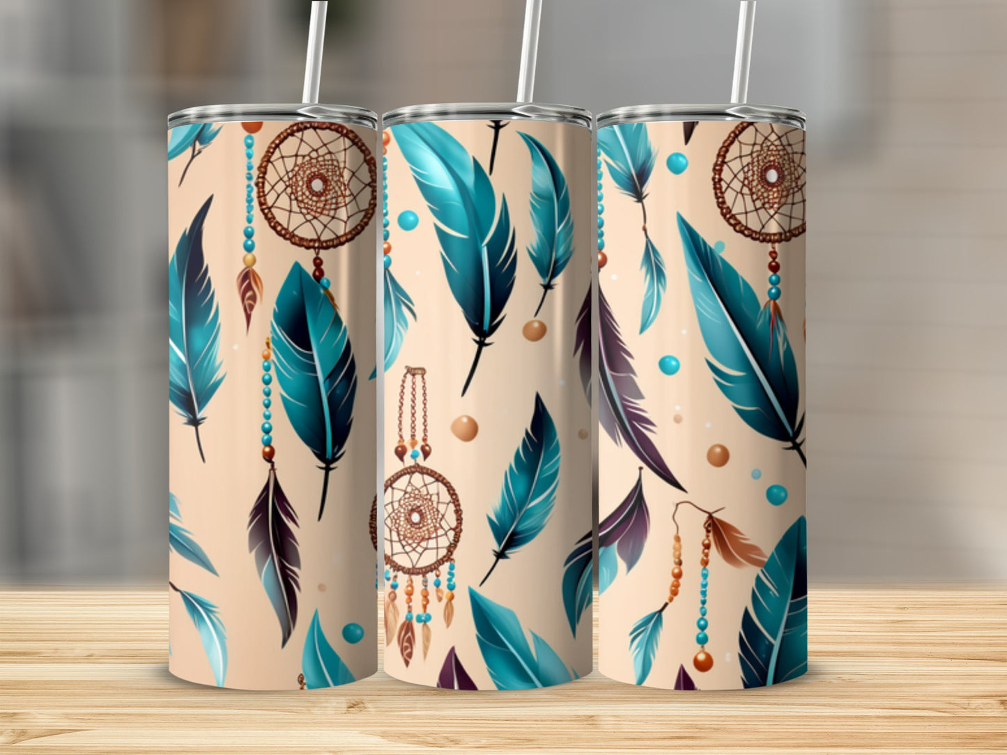 Three tumblers with dreamcatcher and feather designs on a wooden surface.