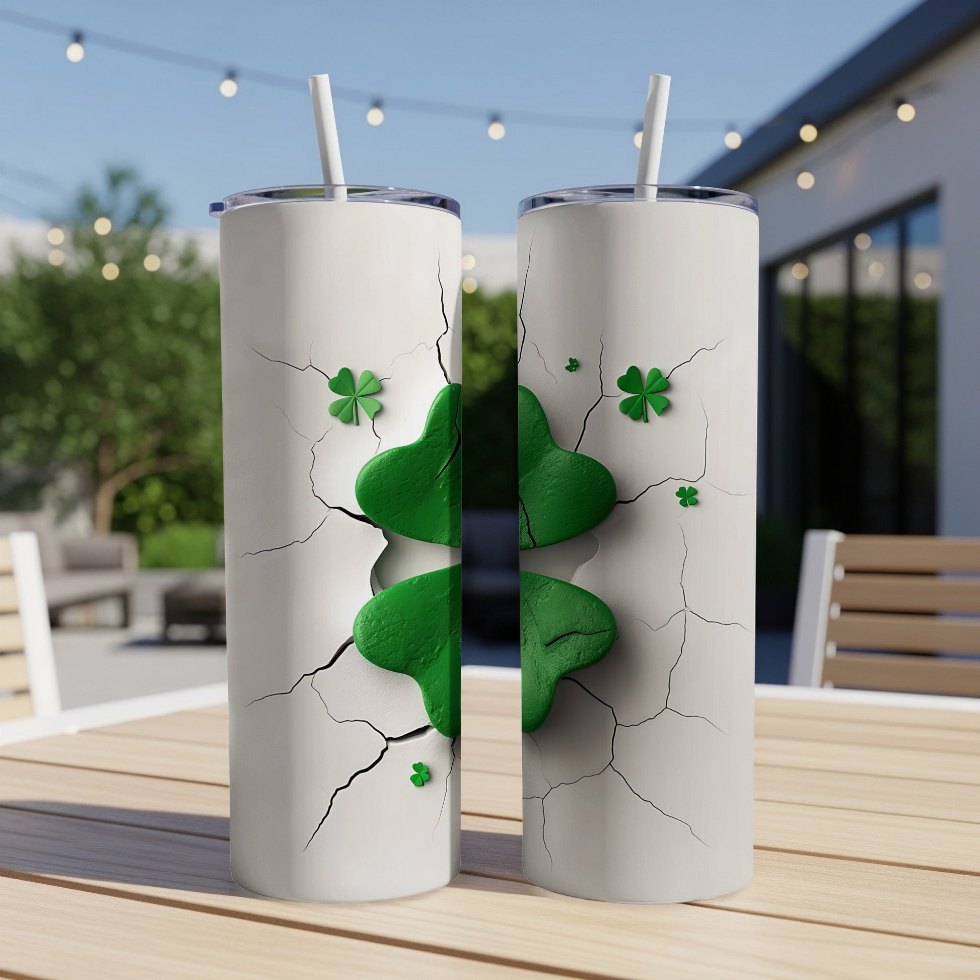 Two cracked white tumblers with green four-leaf clovers on outdoor table.
