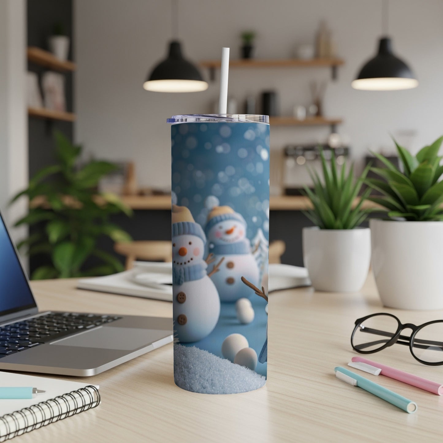 Snowman tumbler with straw on a desk next to a laptop.