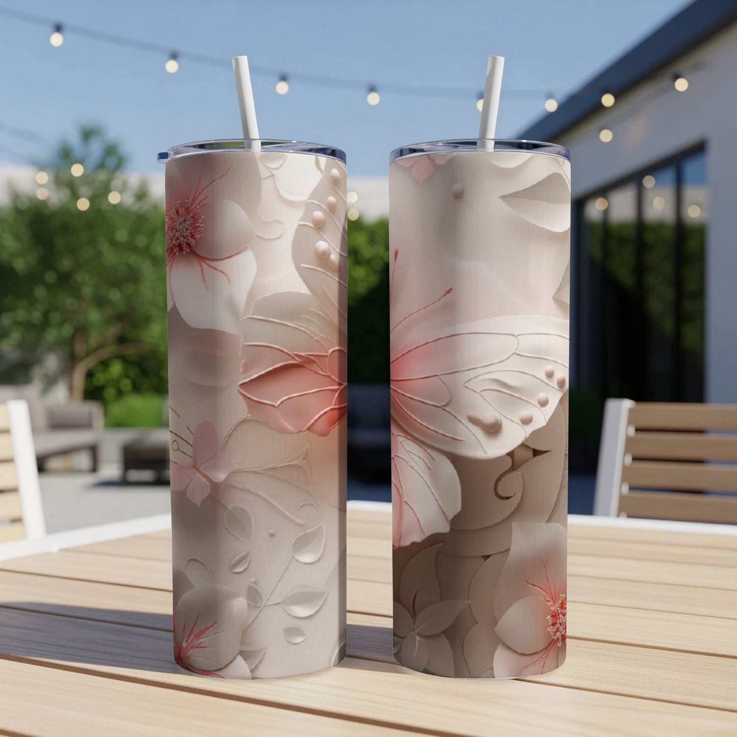 Two floral tumblers with butterflies on a wooden table outdoors.