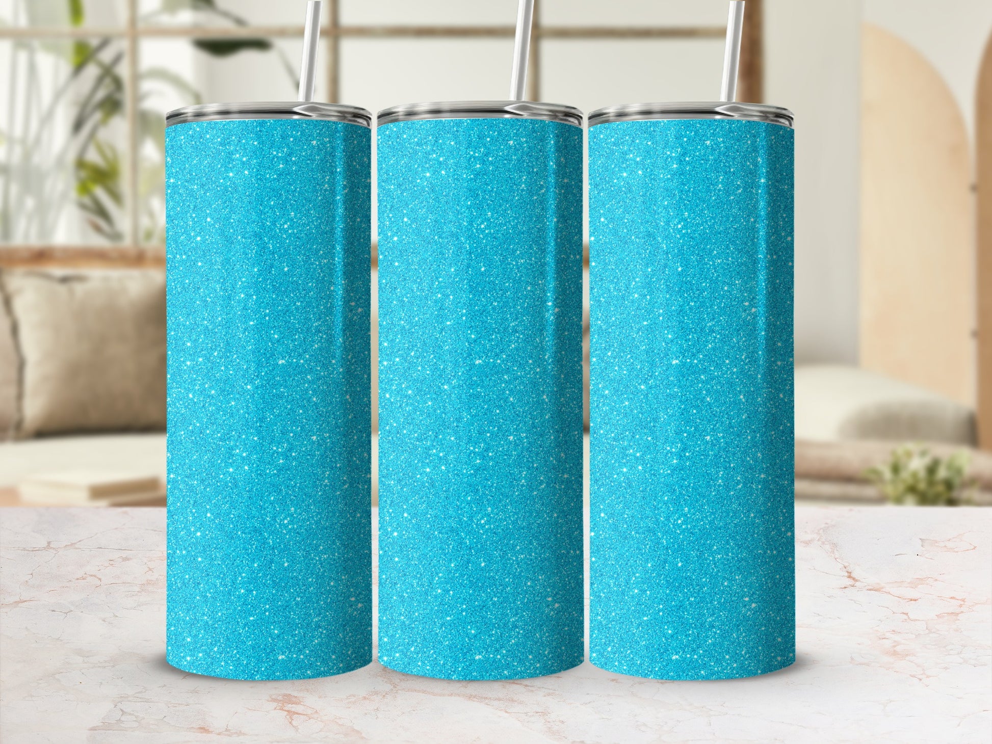 Three blue glitter tumblers with silver lids and straws on a marble surface.