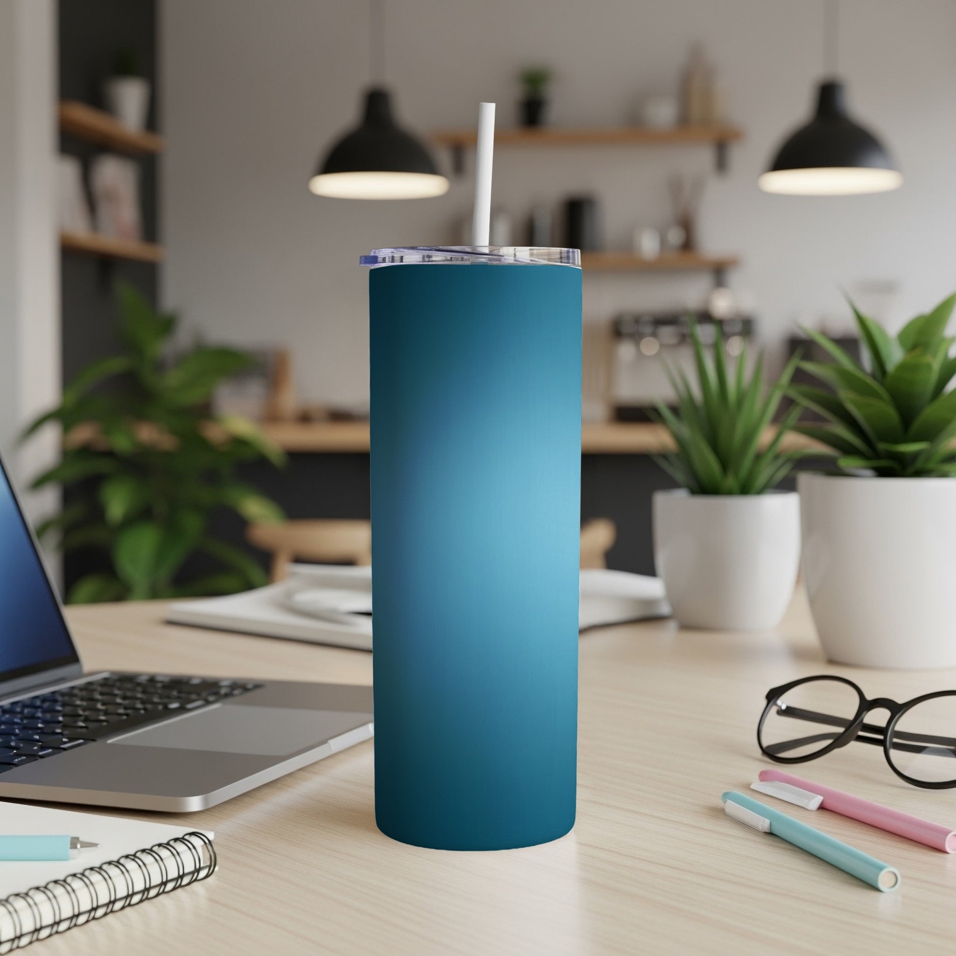 Blue gradient skinny tumbler with white straw on desk.