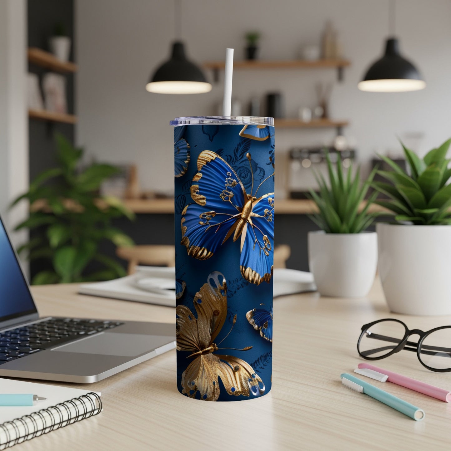 Blue and gold butterflies adorn a tall, narrow tumbler with a straw.