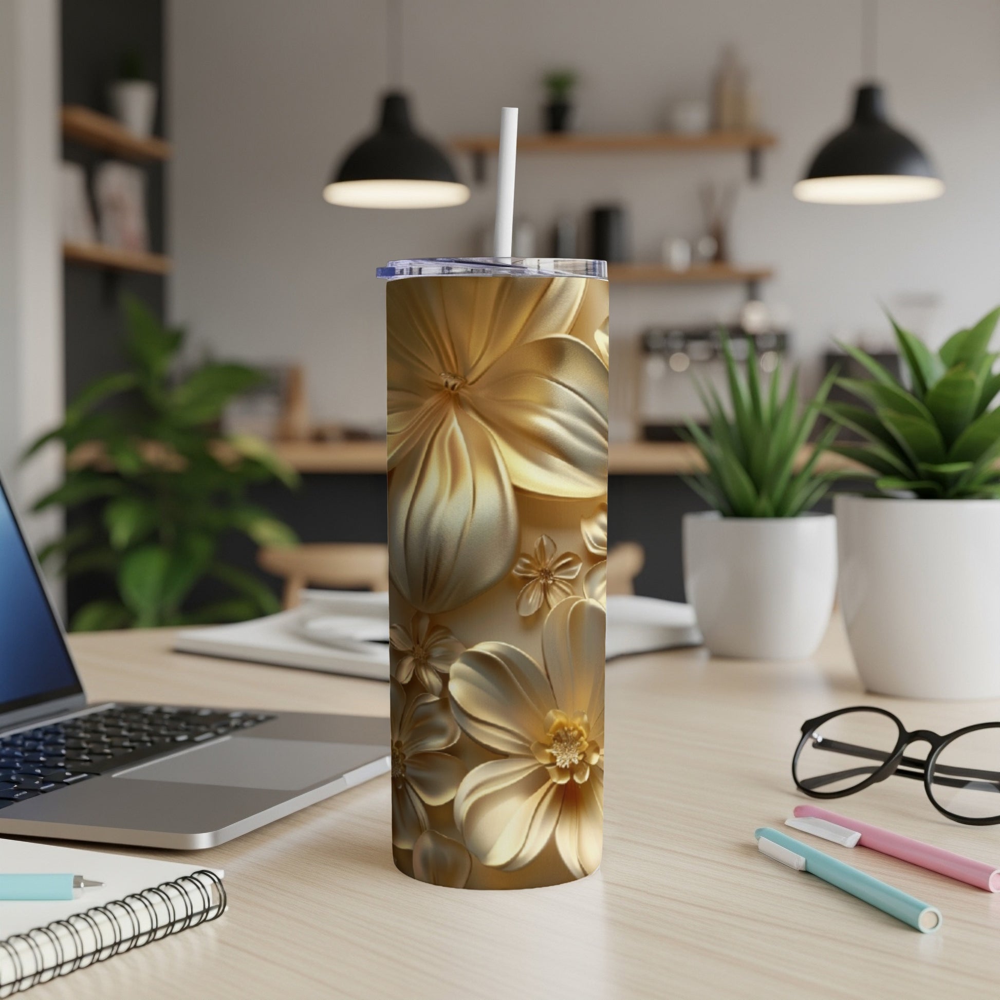 Gold floral tumbler with straw on a desk next to a laptop.