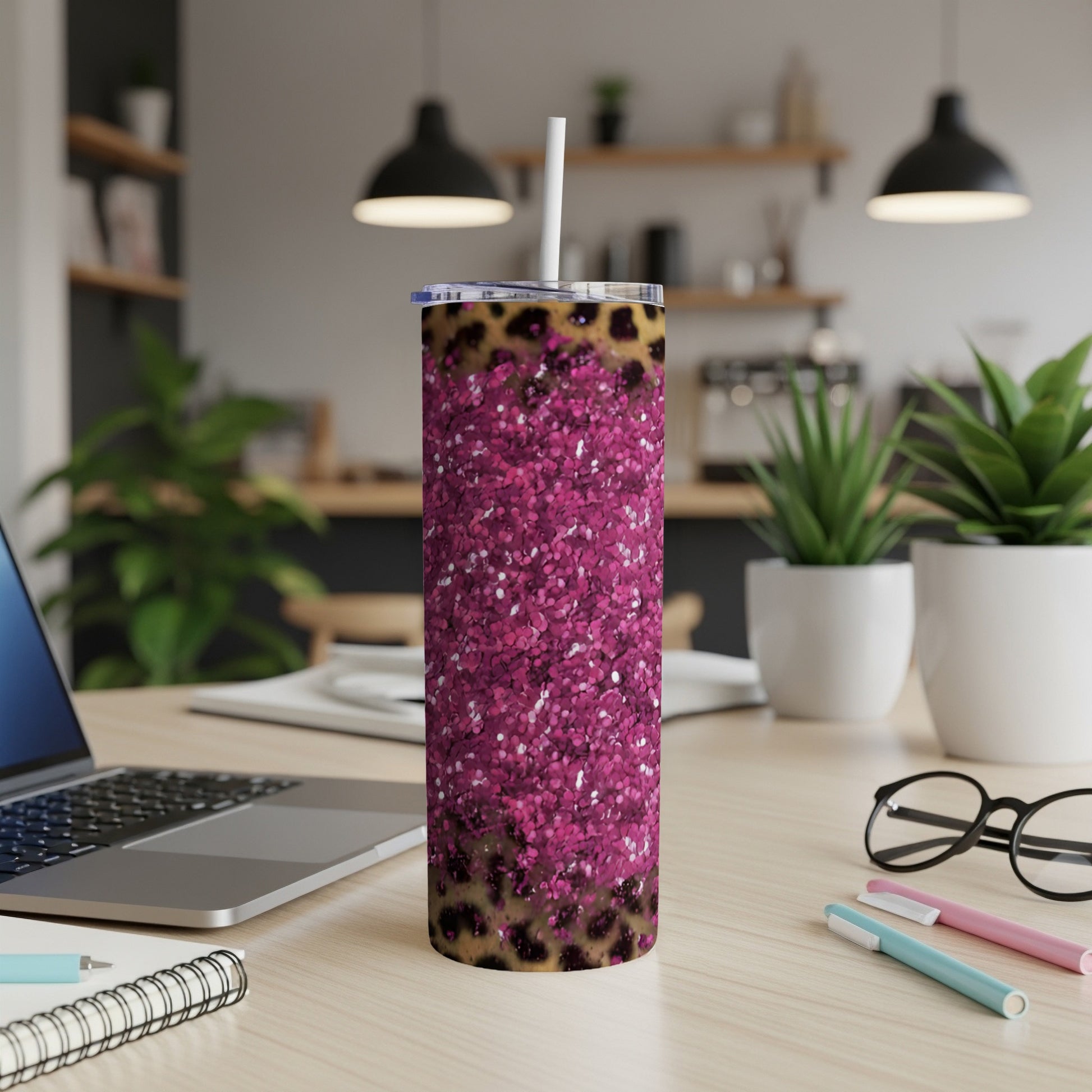 Leopard print and pink glitter tumbler with straw on a desk.