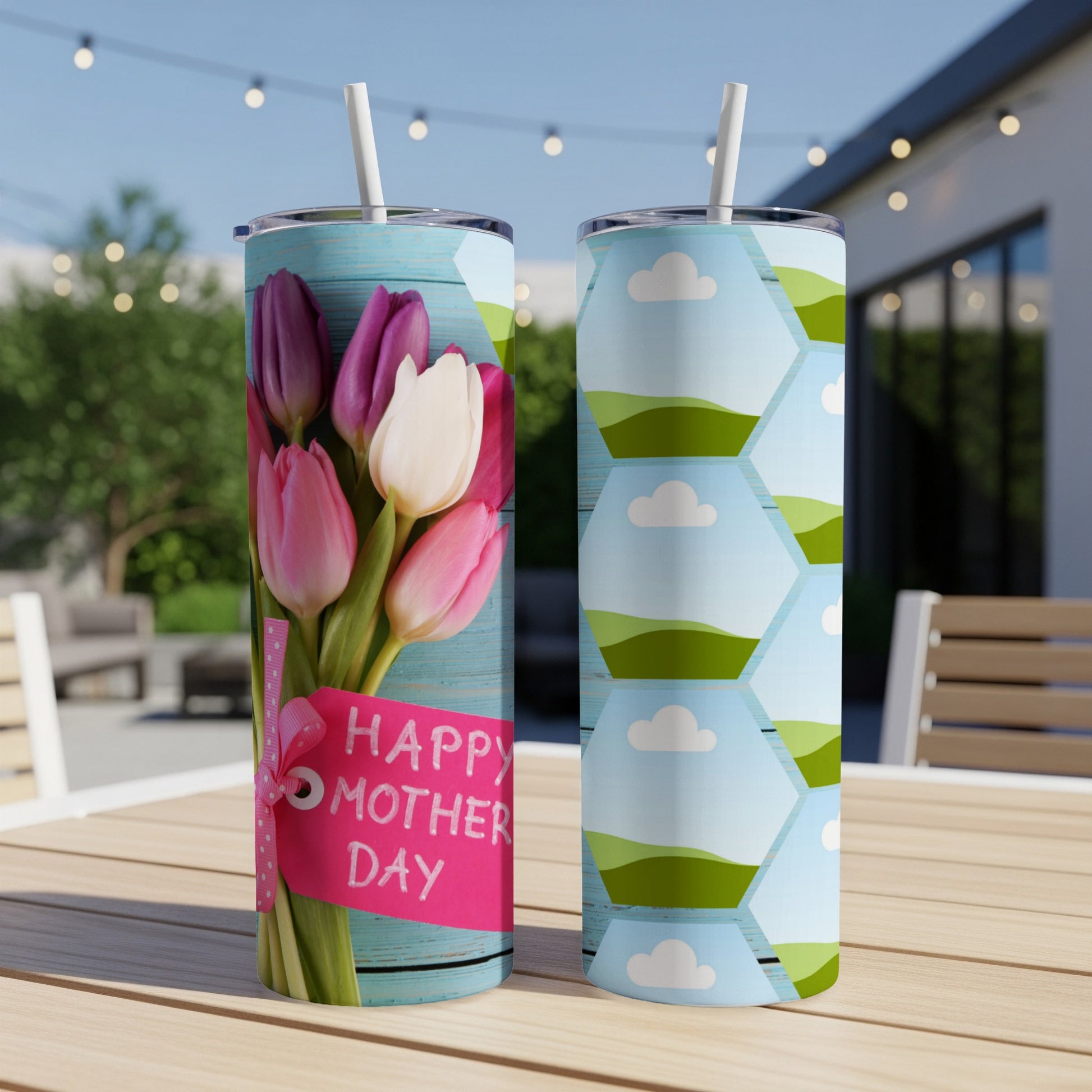 Two tumblers on a table, one with tulips and "Happy Mother Day," the other with clouds and hills.