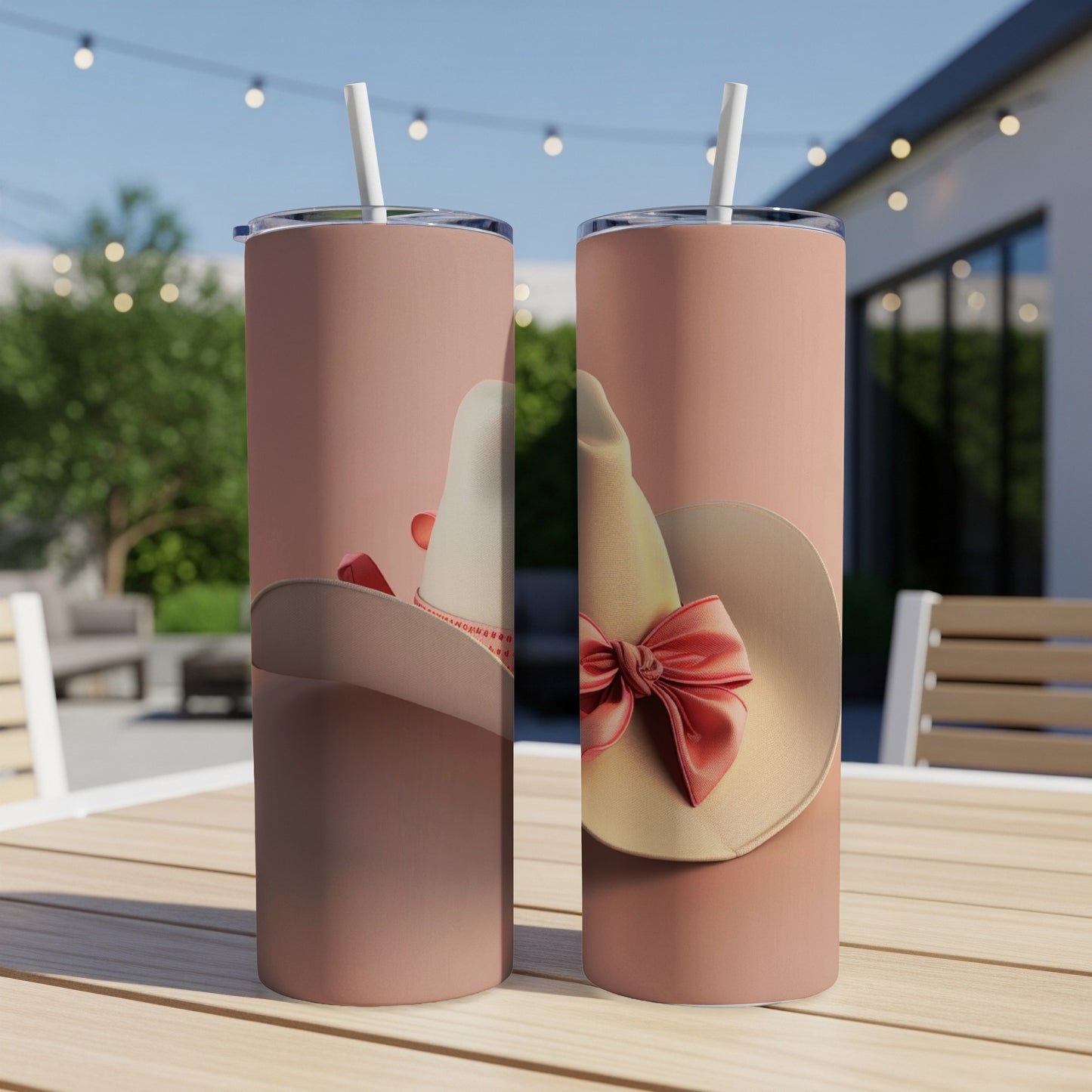 Two pink tumblers with white cowboy hats and red bows on a table.