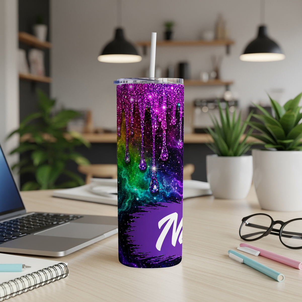 Purple galaxy tumbler with dripping glitter and white "M" on a desk.