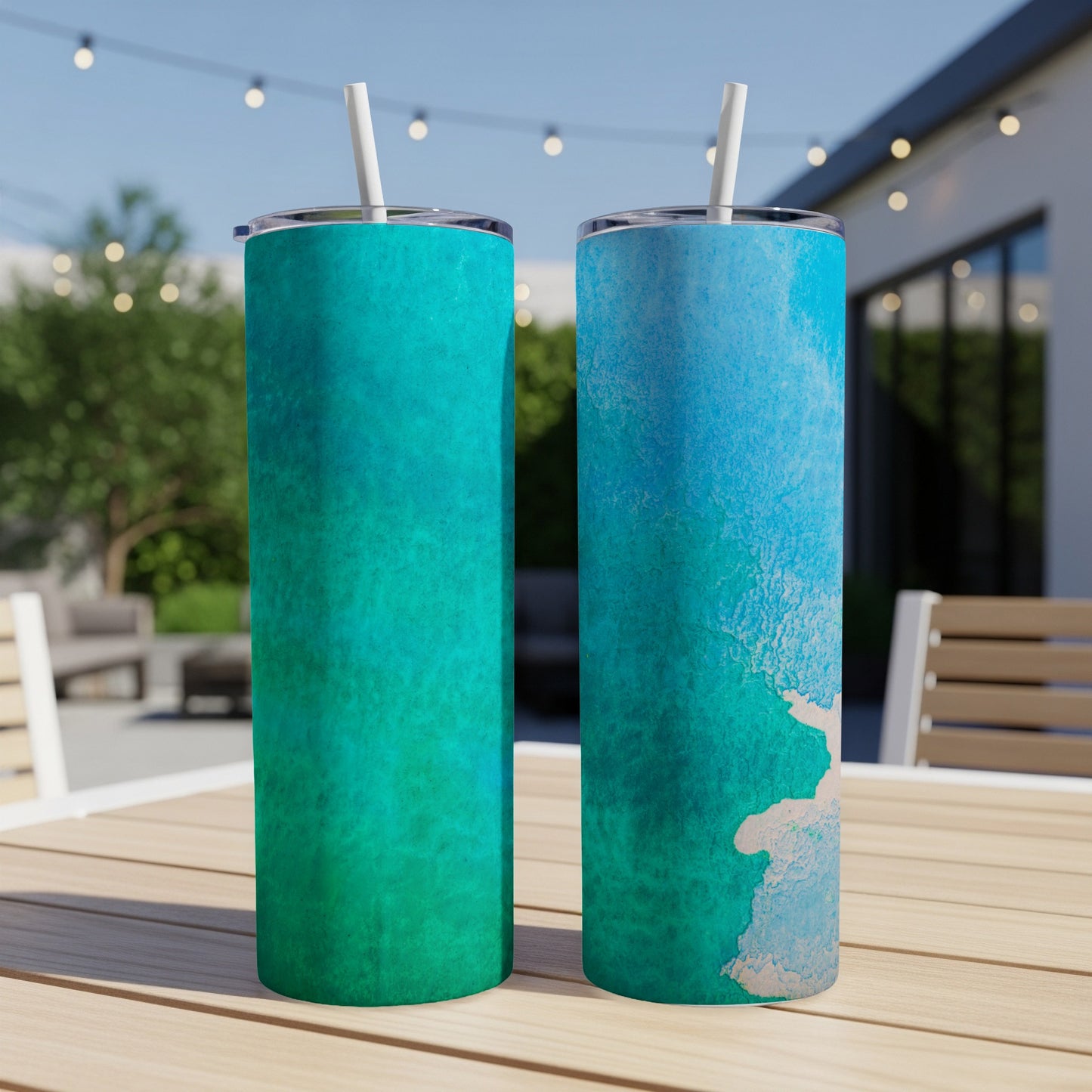 Two tumblers with teal and blue watercolor designs sit on a table.