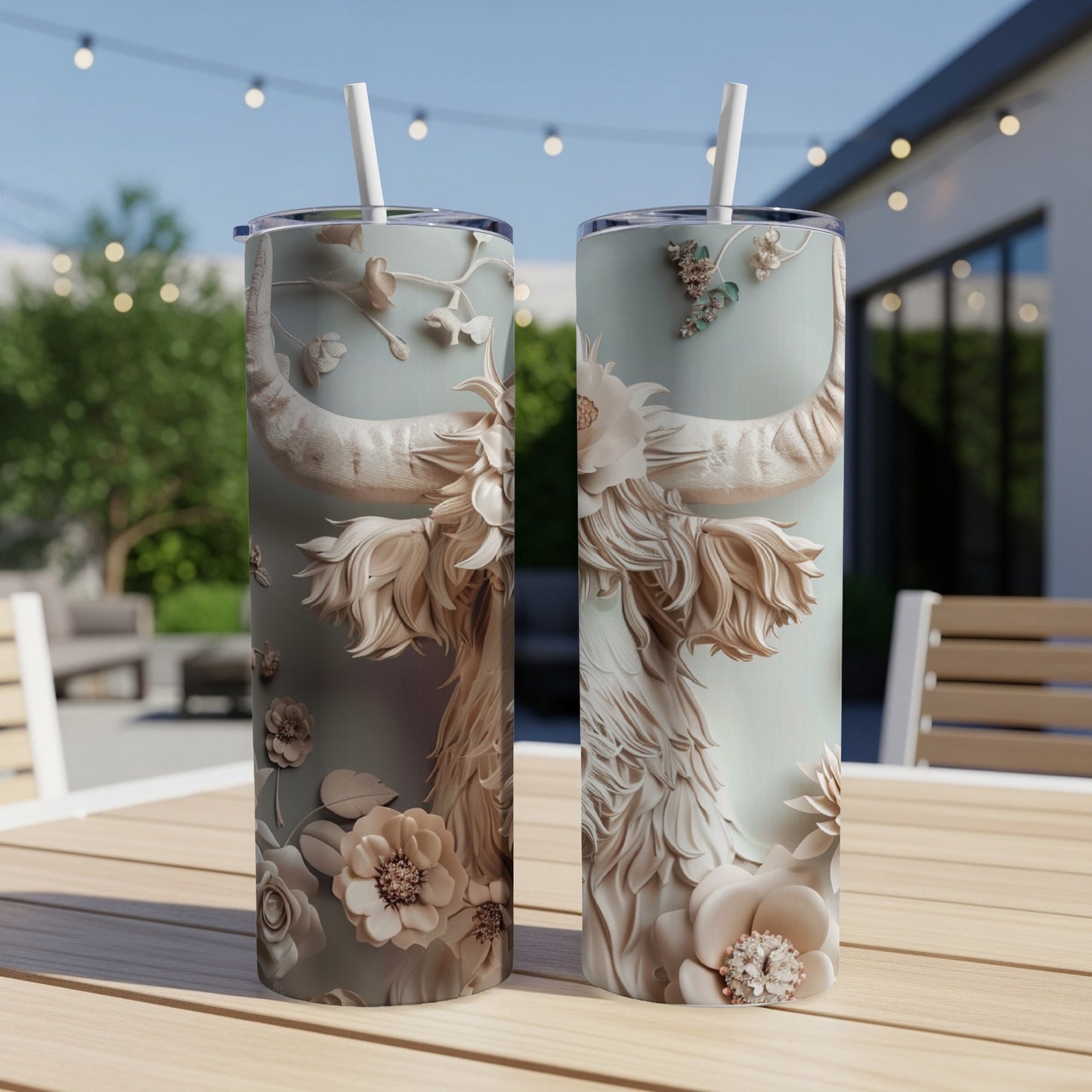Two tall tumblers with embossed floral and bull horn designs on a table.