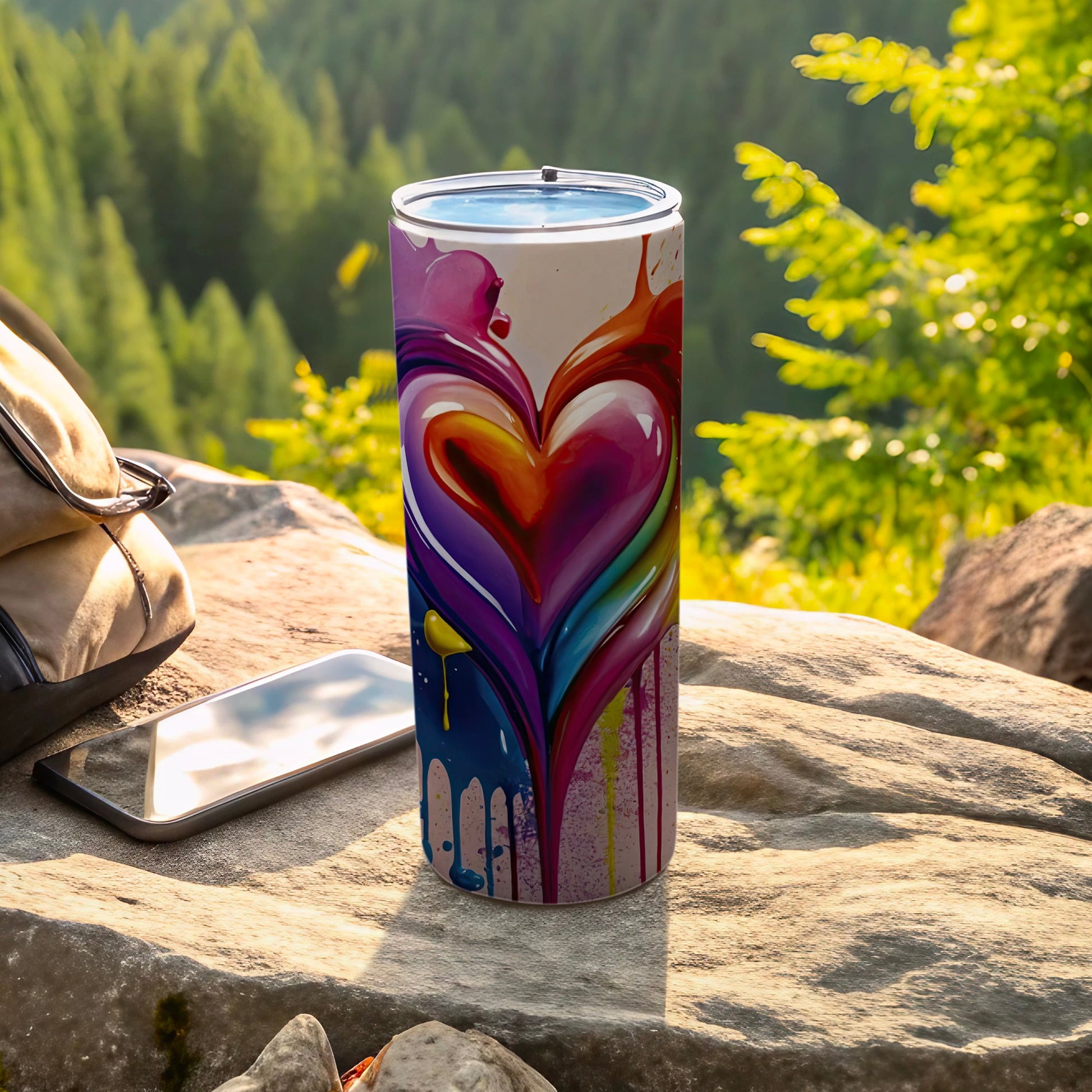Tall insulated tumbler with colorful dripping heart design on a rock.