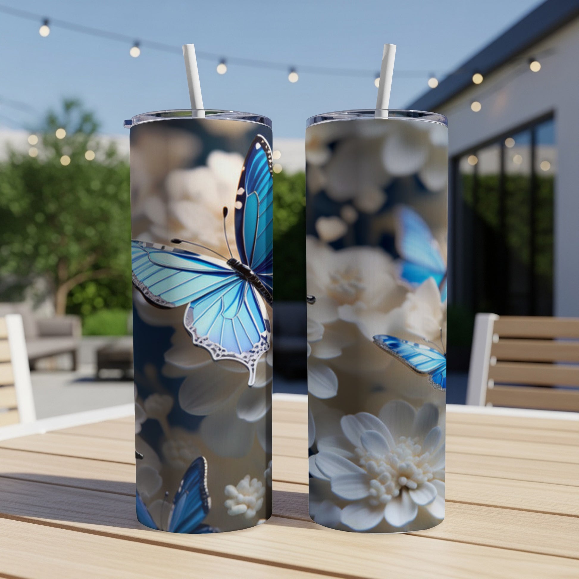Two tumblers featuring blue butterflies and white flowers on a patio table.