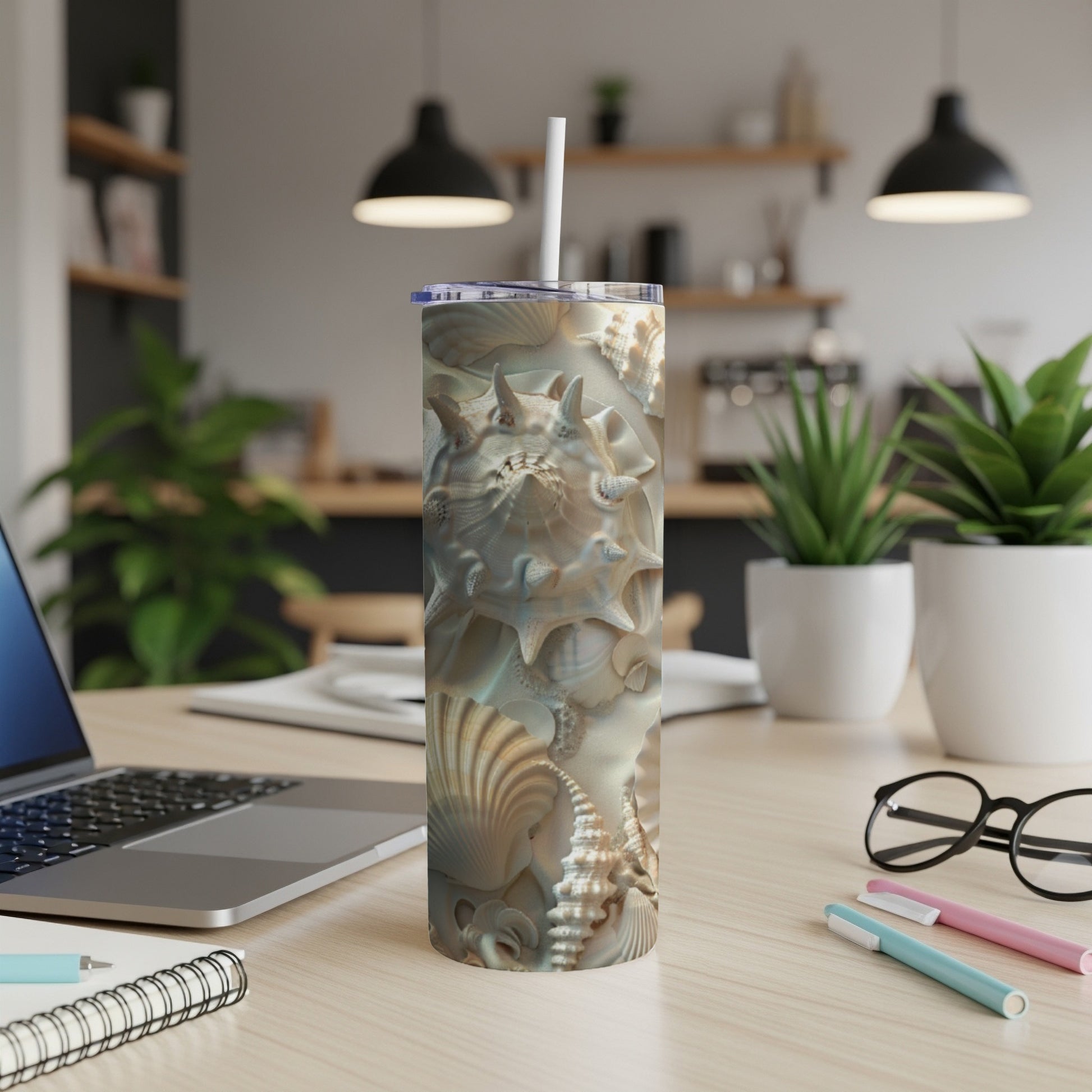 Seashell and seahorse pattern on a tall, white tumbler with a straw.